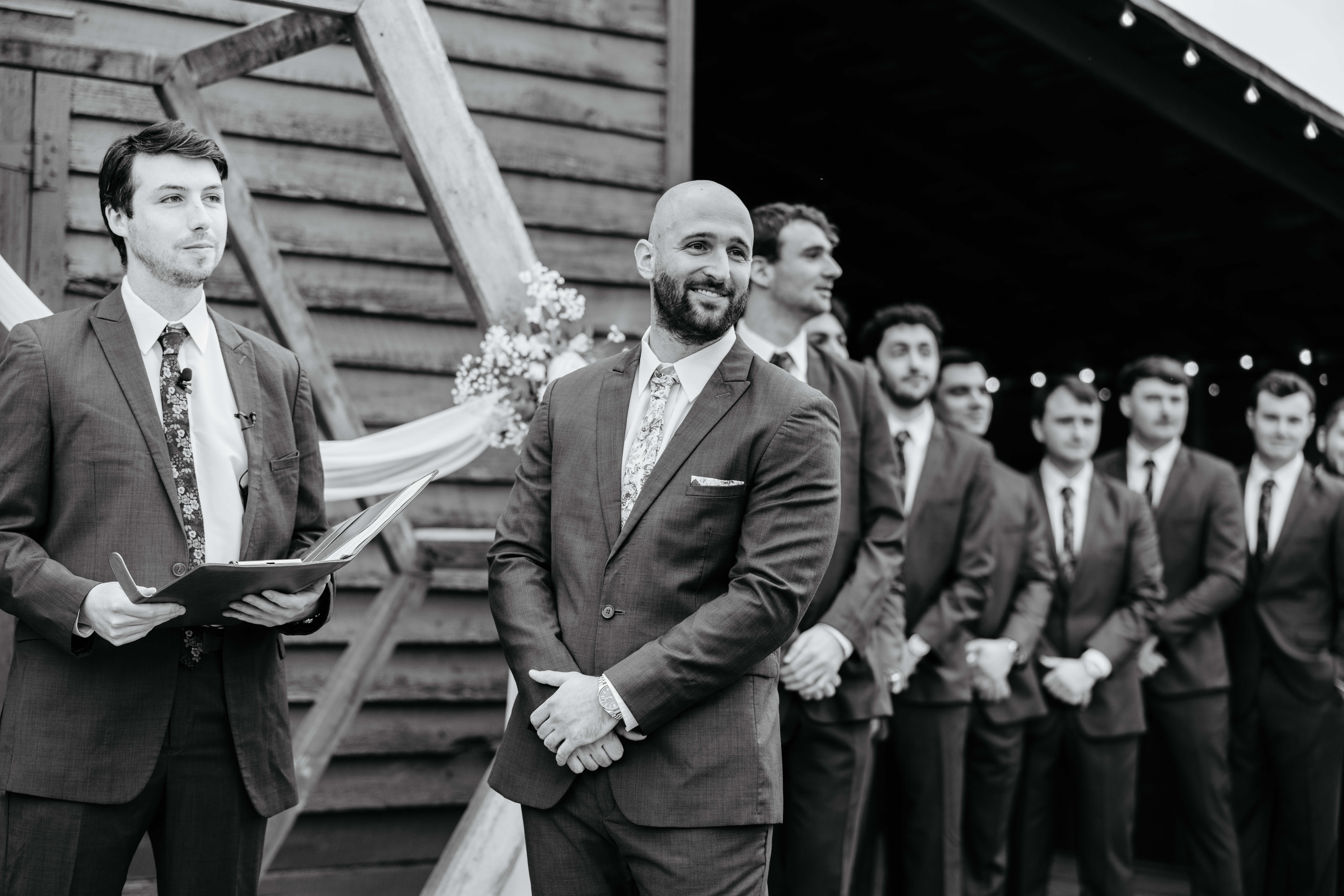 Barns of Kanak October Wedding 25 Black and white photo of groom smiling towards end of aisle, groomsmen and officiant in photo all in suits