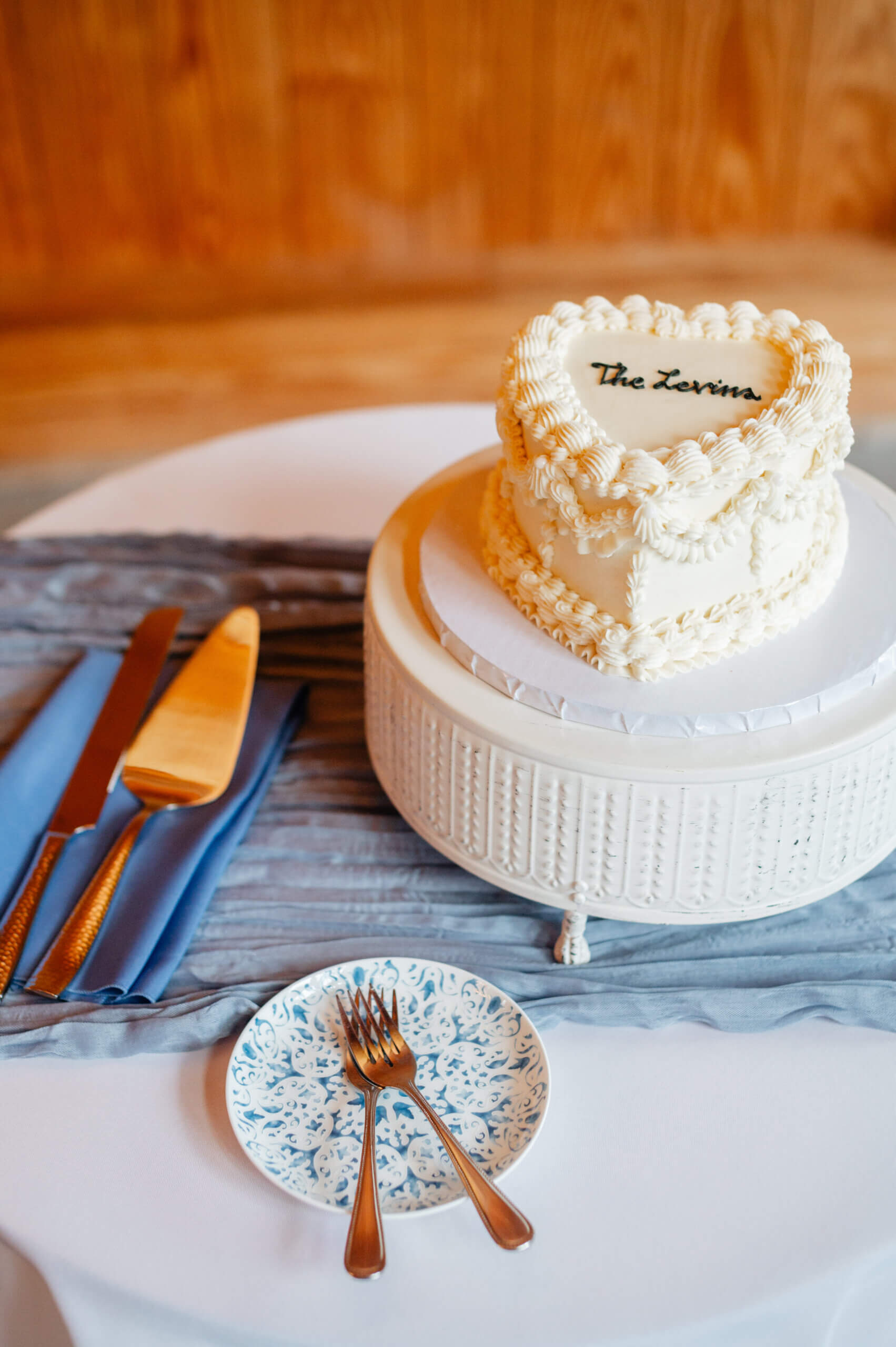 Barns of Kanak October Wedding 32 Small white wedding cake in shape of a heart with vintage piping techniques sits on a white cake stand, in black icing on top reads The Levins