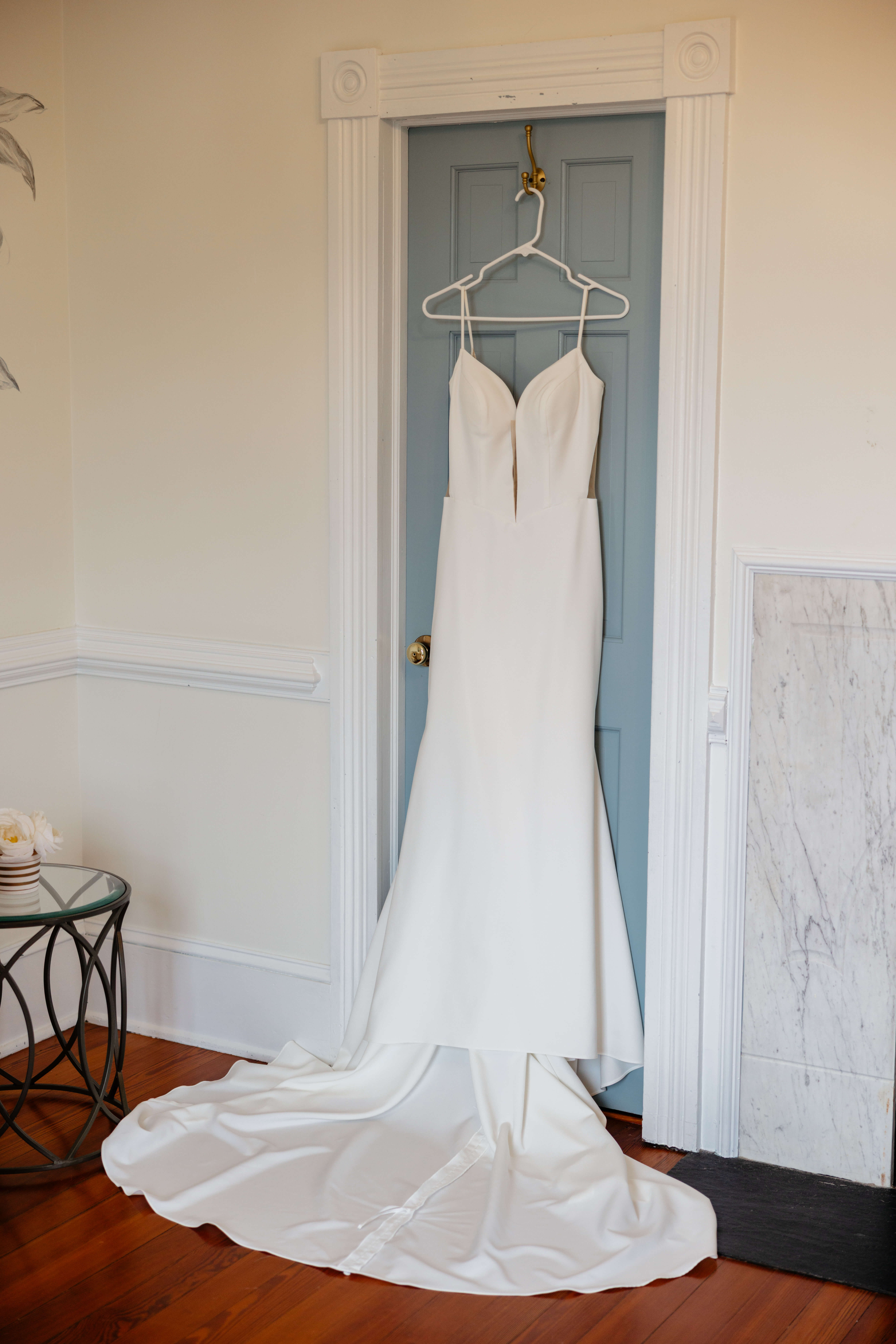 Barns of Kanak October Wedding 3 Bride's white wedding dress hangs on light blue colored door, train fanned out on floor