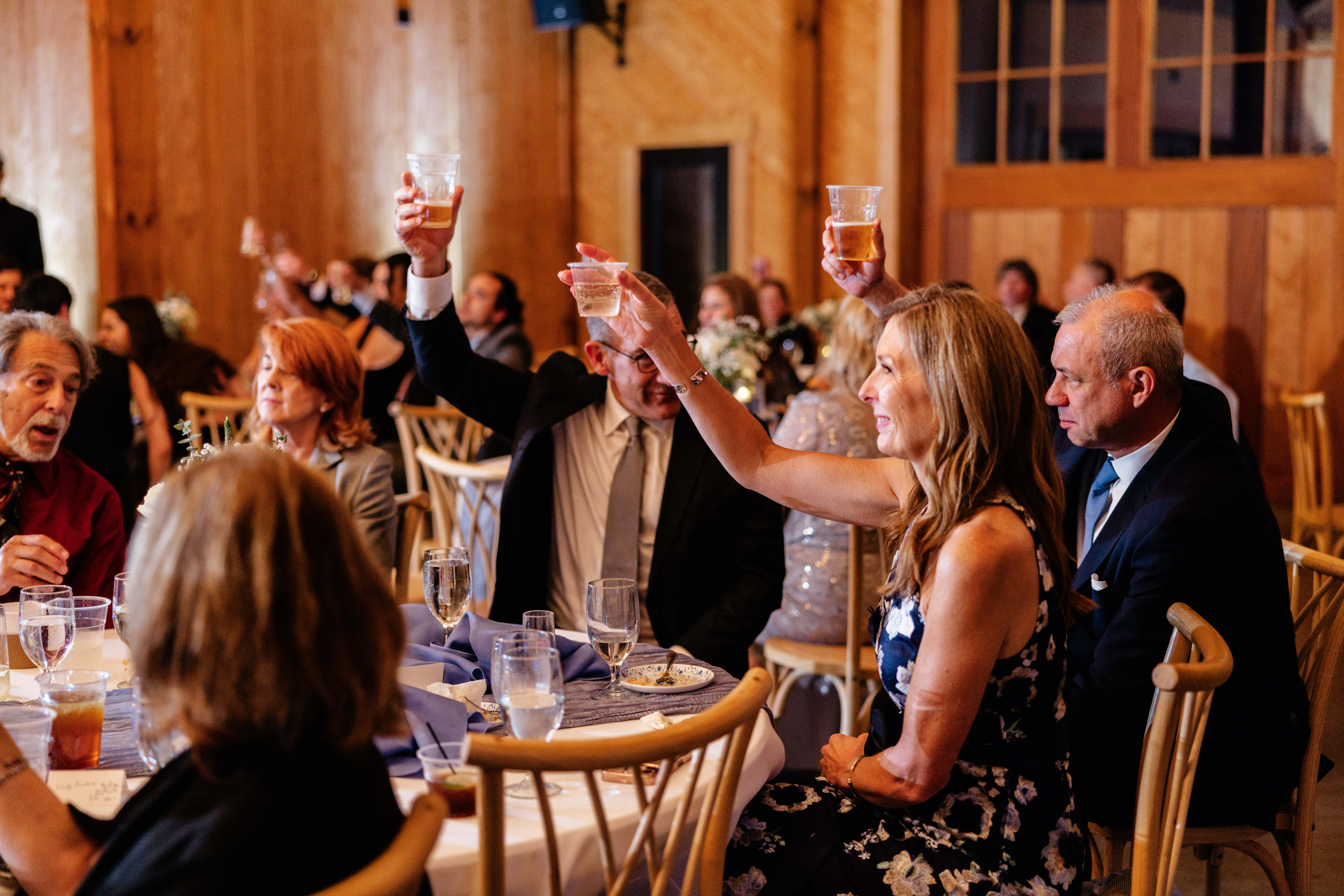 Barns of Kanak October Wedding 52 Guests sitting at tables hold their glasses up in their air