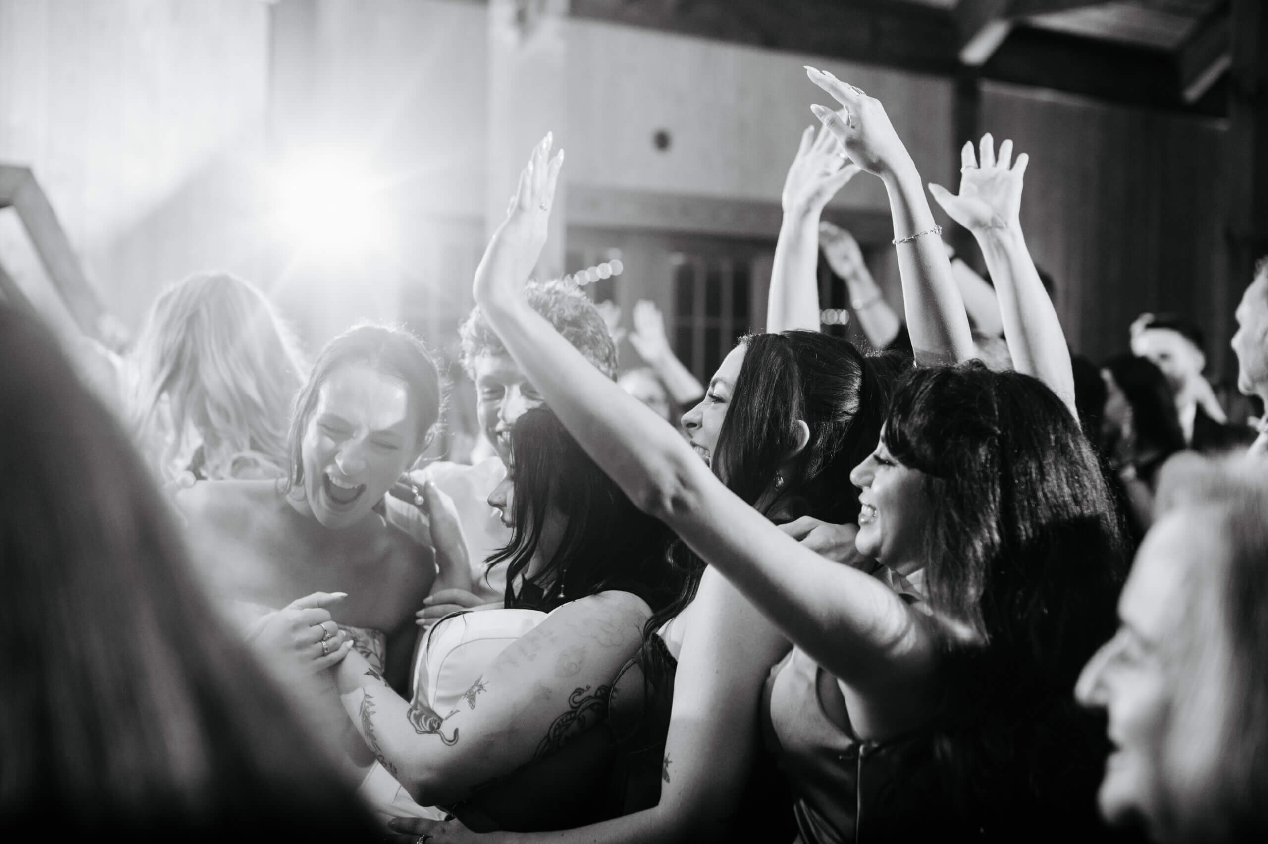 Barns of Kanak October Wedding 53 Black and white photo of bride dancing with her bridesmaids on dance floor all smiling and laughing, throwing their hands up in air