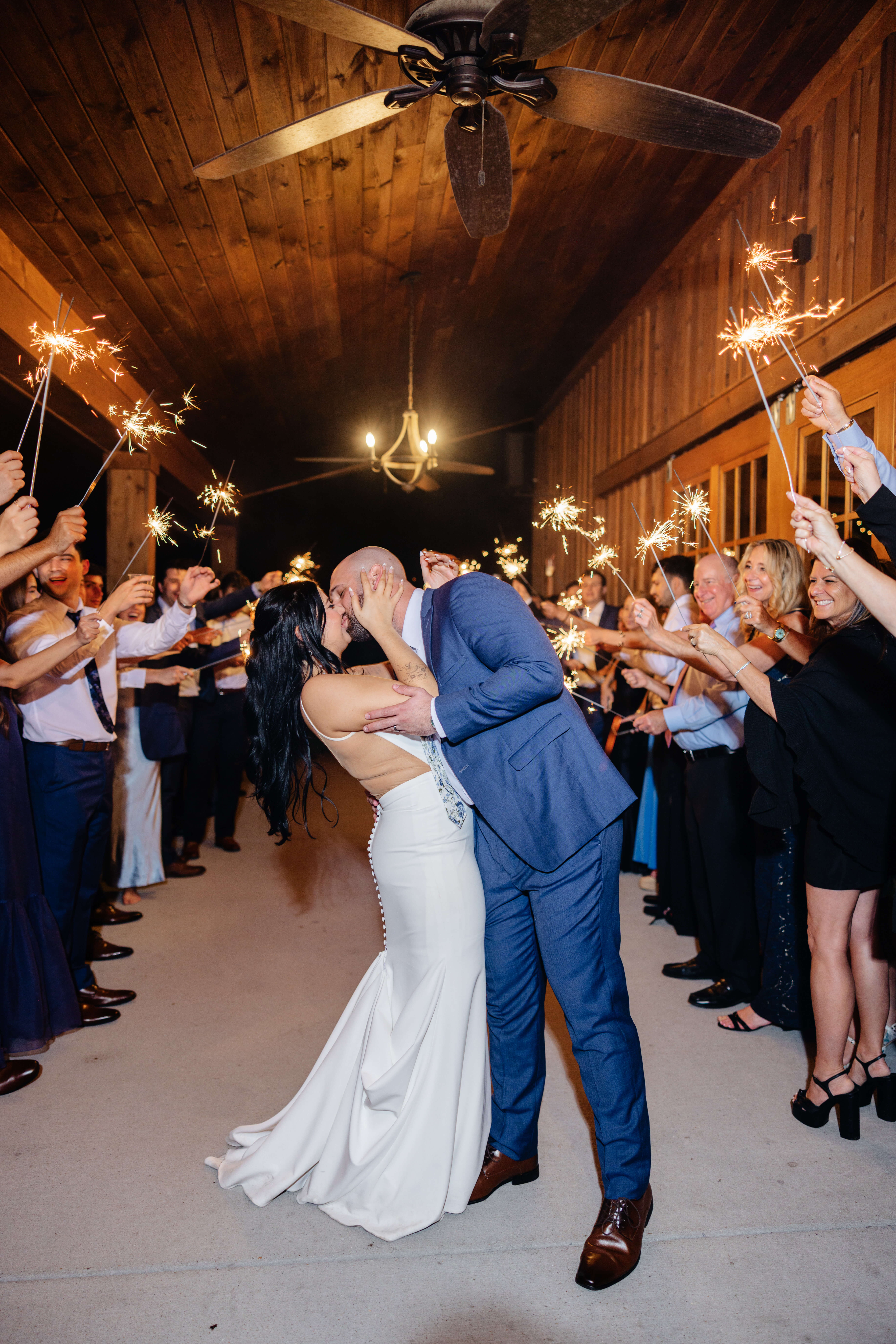 Barns of Kanak October Wedding 56 Bride and groom kiss during their exit from reception, guests and family all holding sparklers cheering and smiling