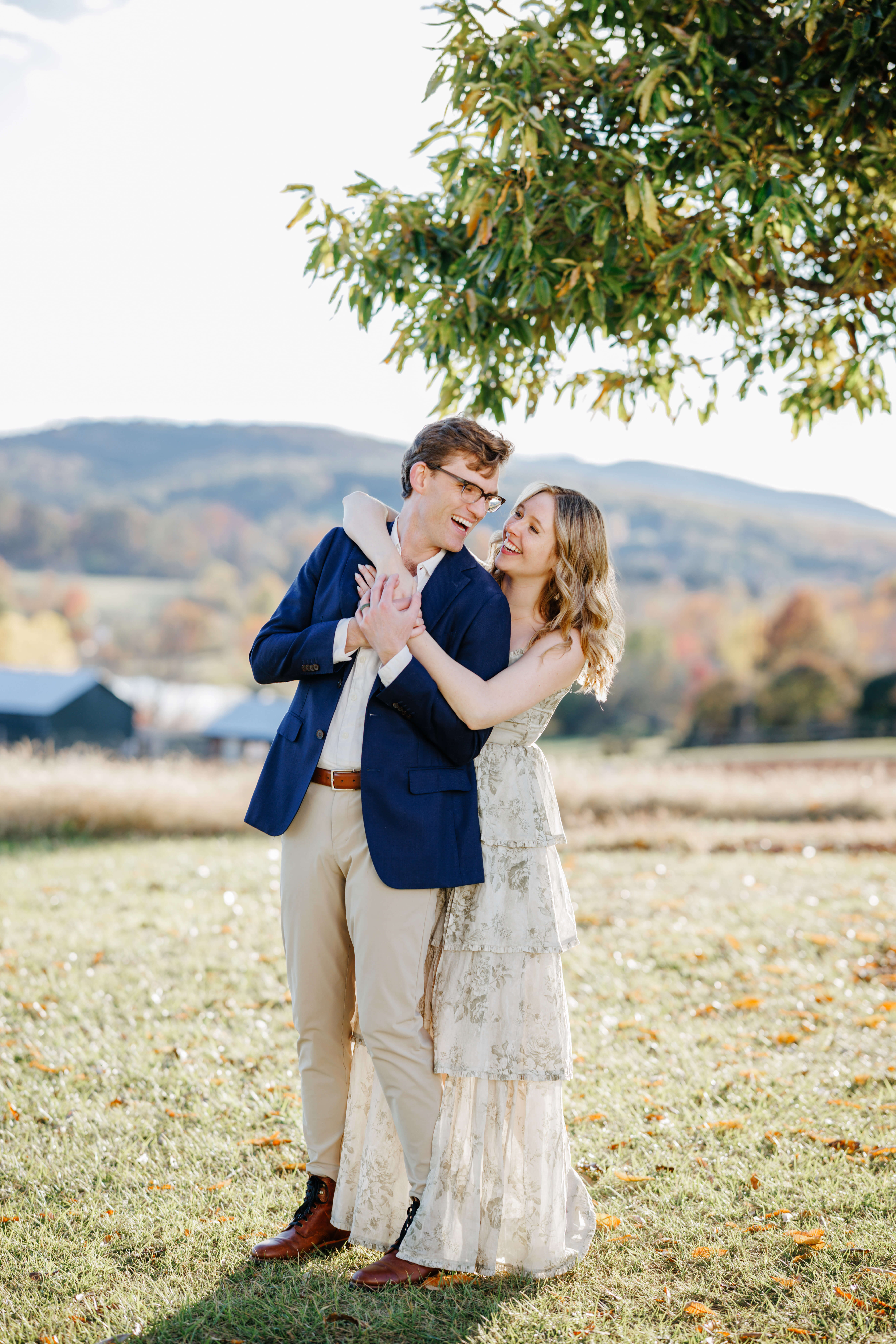 Market at Grelen Fall Engagement Photography 11 Woman standing behind her fiance as she wraps her arms around him, he looks over his shoulder to smile at her