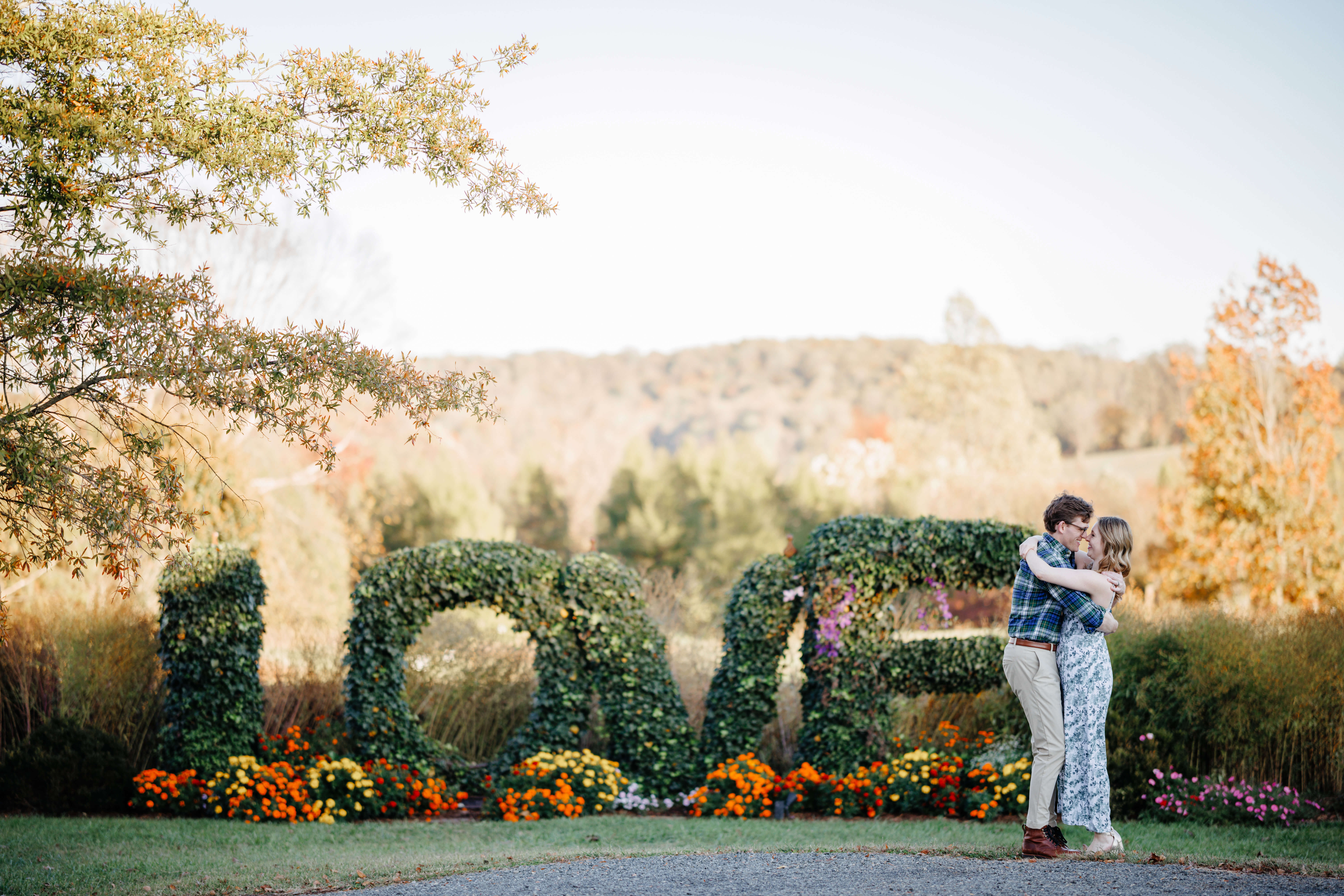 Market at Grelen Fall Engagement Photography 17 Large letters spell out LOVE made of plants and leaves, couple stands beside letters with their arms wrapped around one another