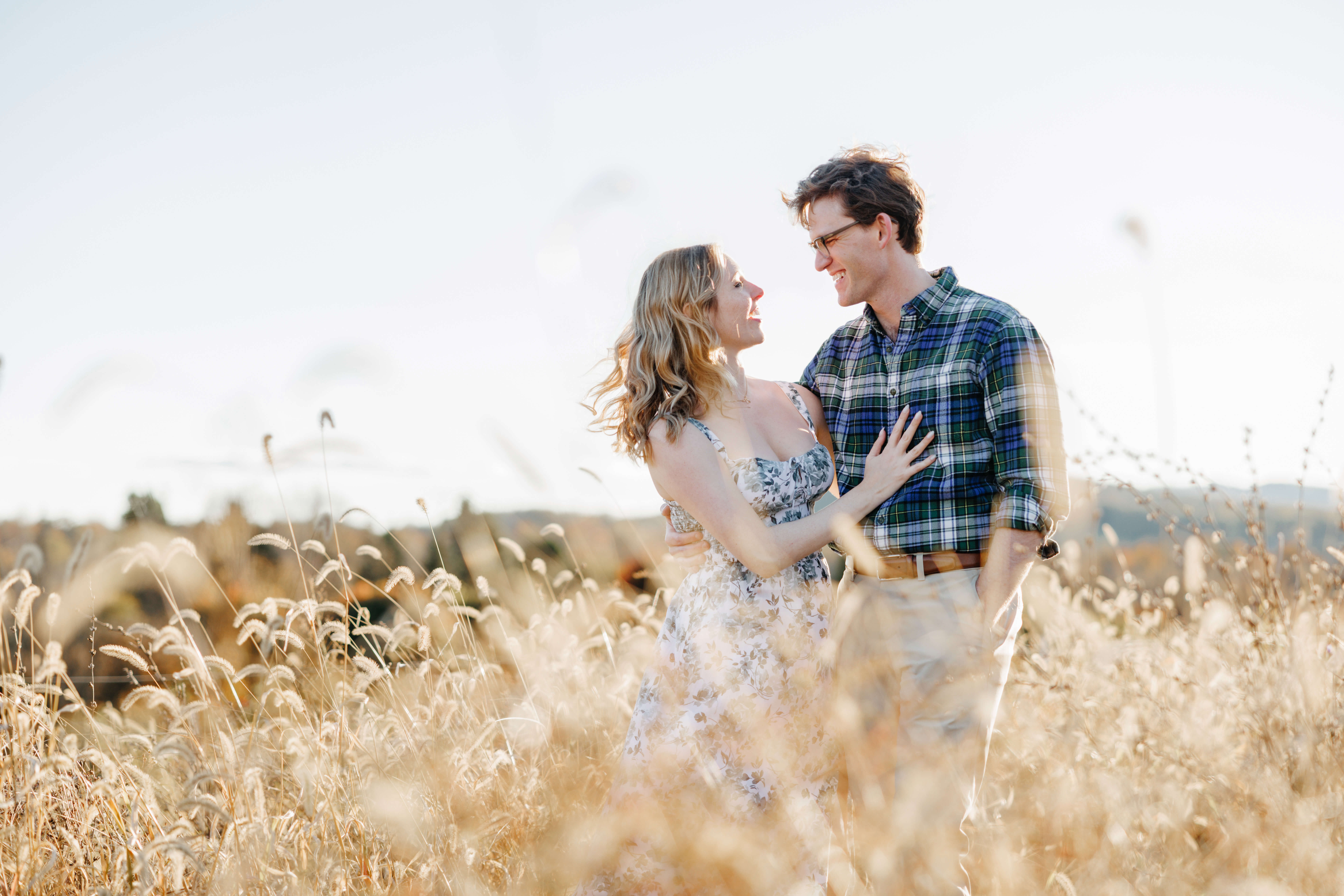 Market at Grelen Fall Engagement Photography 21 Man and woman smiling at one another, woman's hand on man's chest as they stand in a field at market at grelen