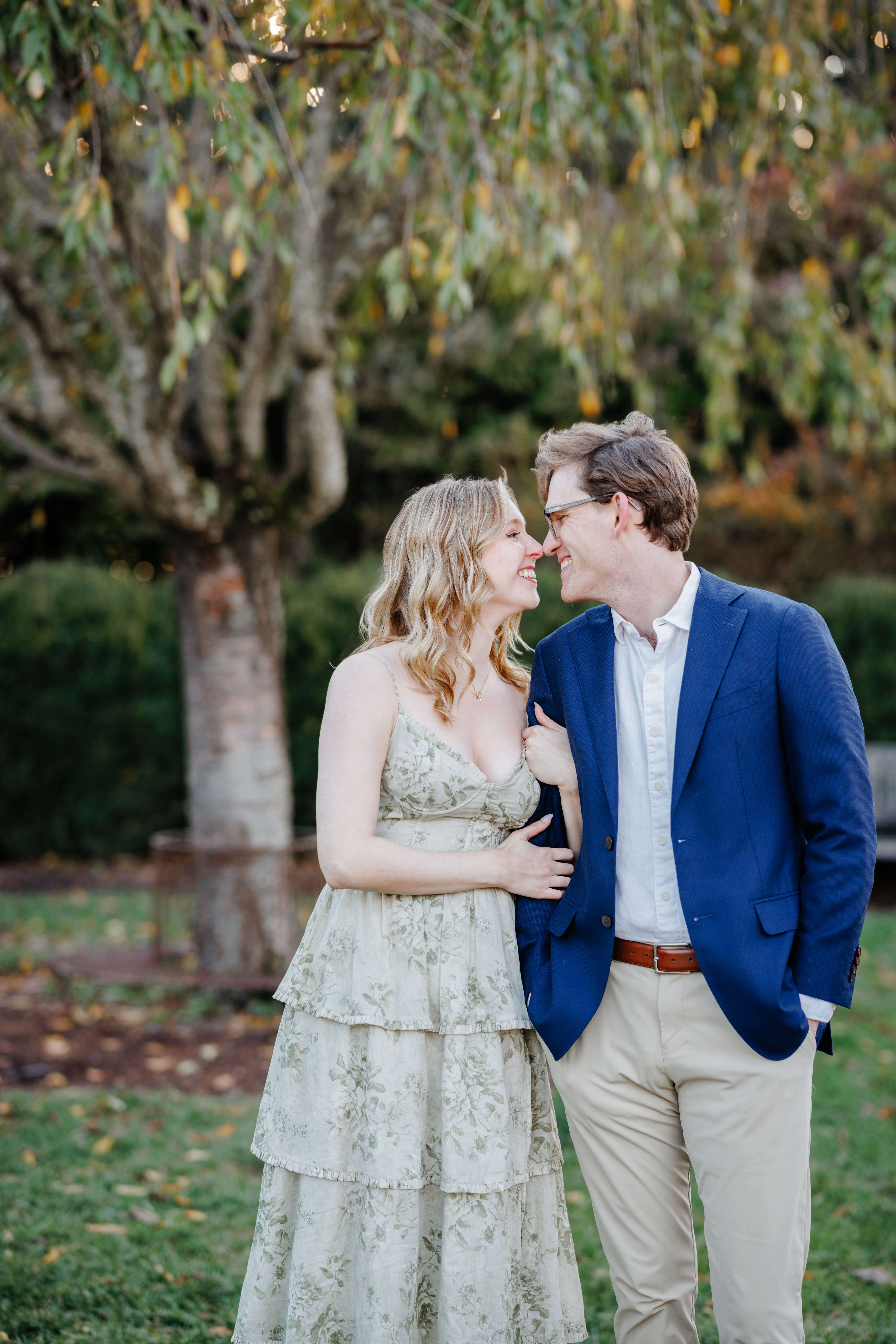 Market at Grelen Fall Engagement Photography 9 Woman holding on to her fiance's arm as they smile at each other and touch noses