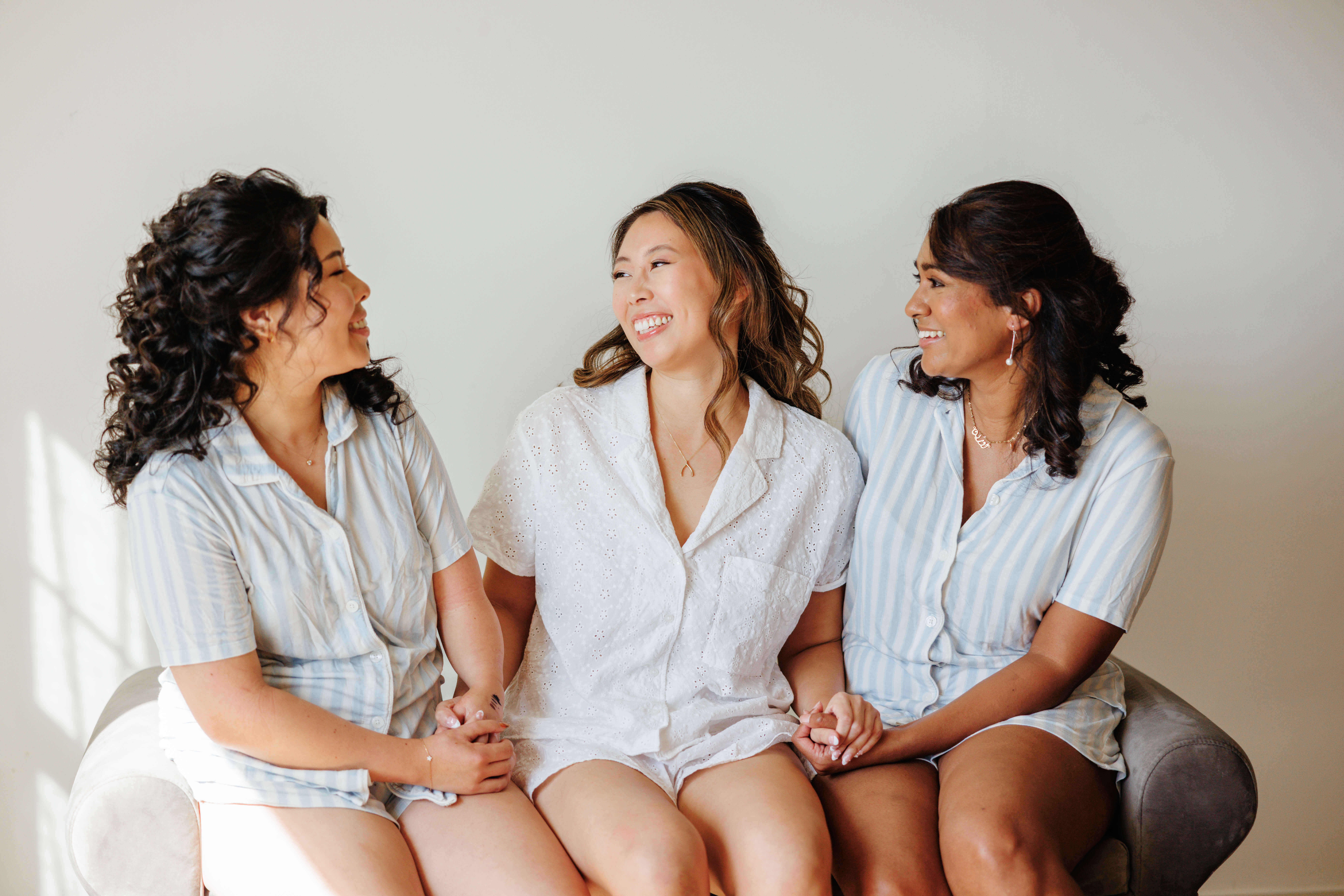 Valley Road Vineyard Fall Wedding 4 Bride sits with two of her bridesmaids holding hands and smiling