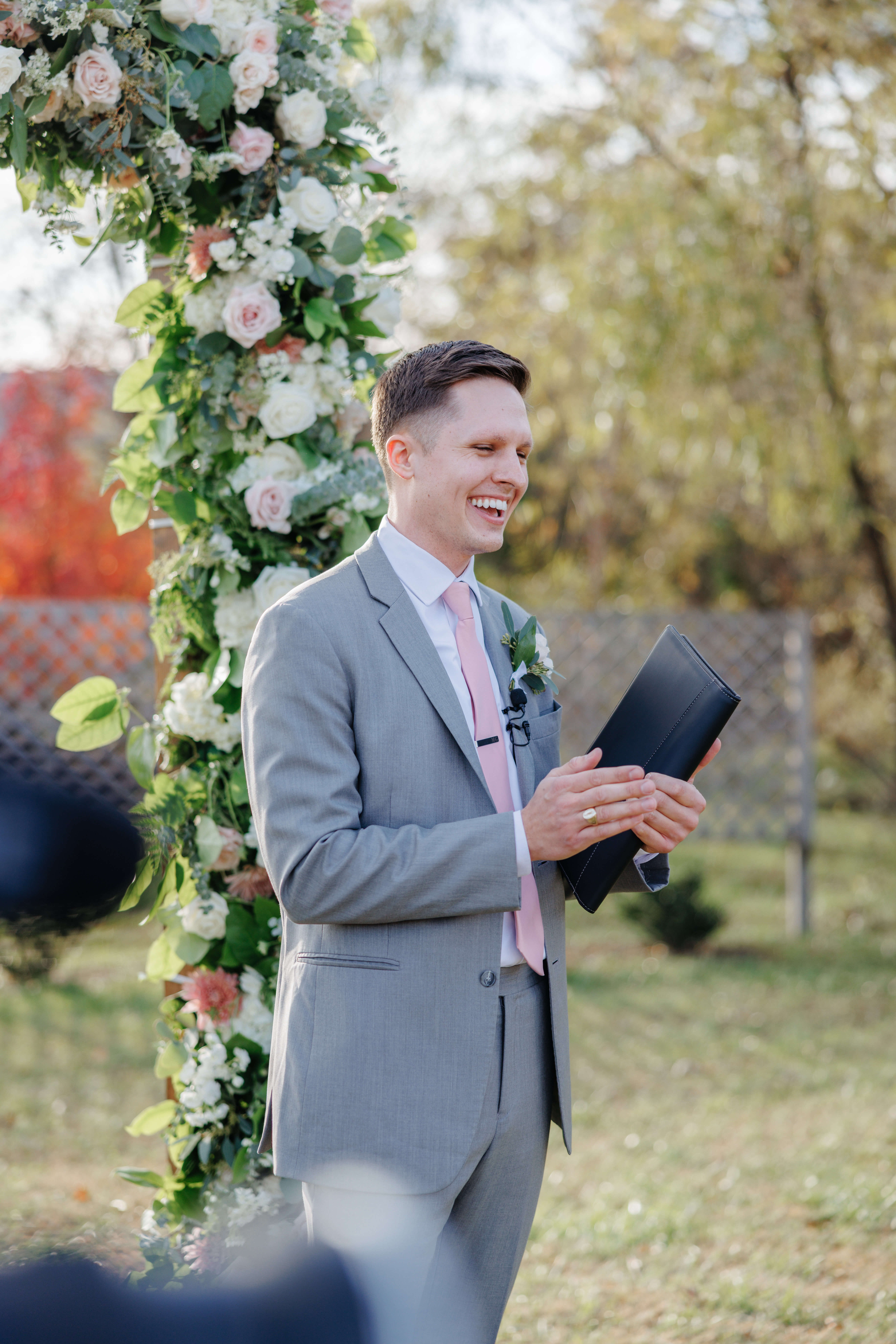 Valley Road Vineyard Fall Wedding 19 Officiant stands at altar in a grey suit with pink tie