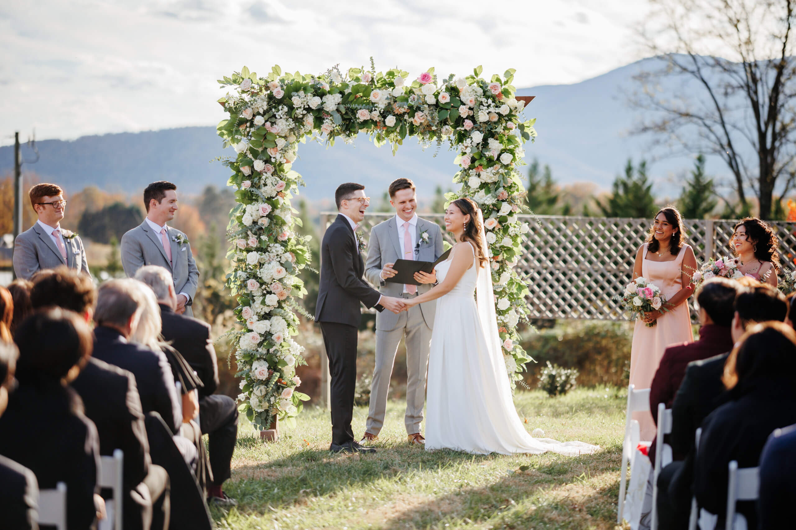 Valley Road Vineyard Fall Wedding 24 Bride and groom hold hands during their ceremony, bride smiling and groom laughing