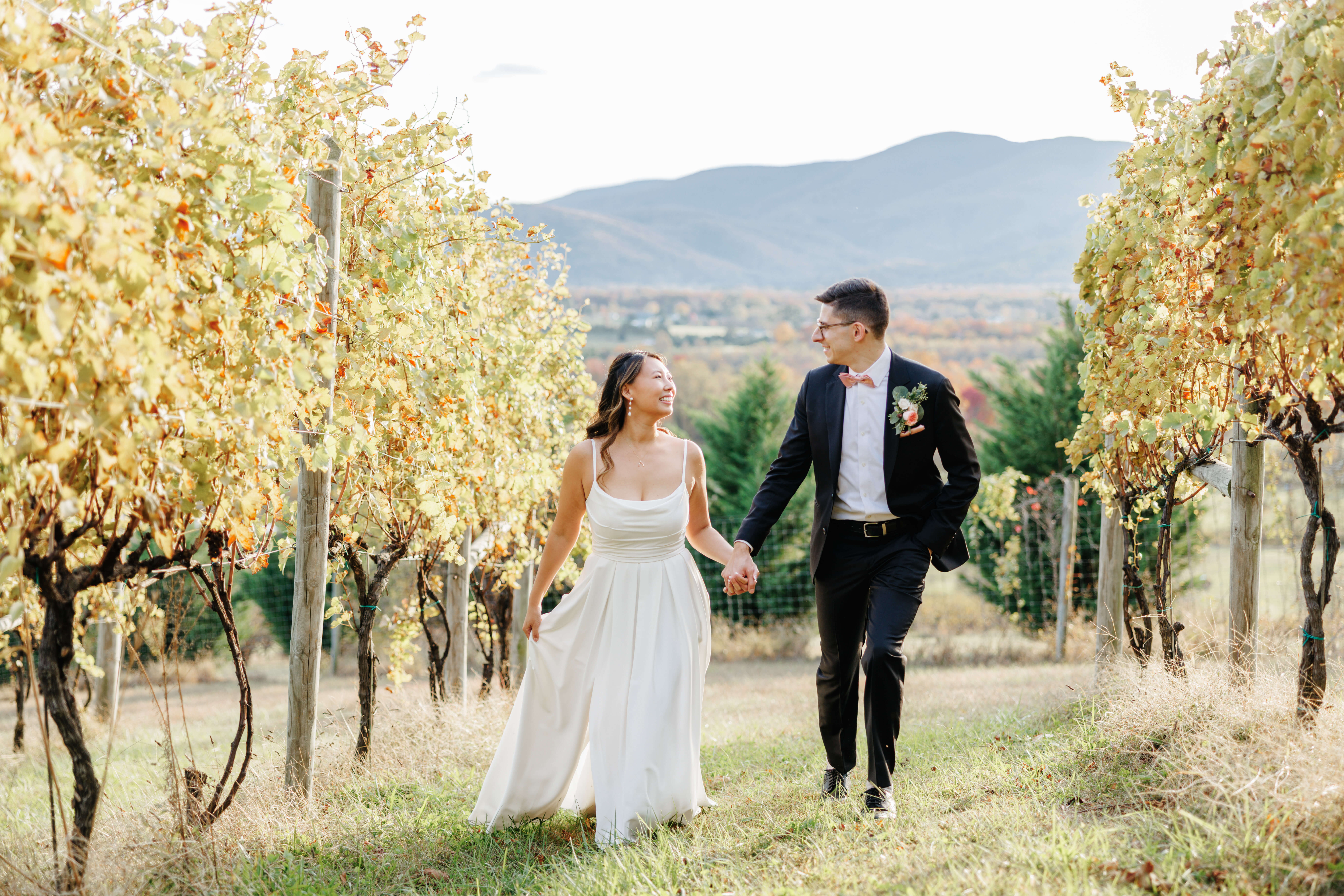 Valley Road Vineyard Fall Wedding 34 Bride and groom walking through the vineyards holding hands and smiling at each other