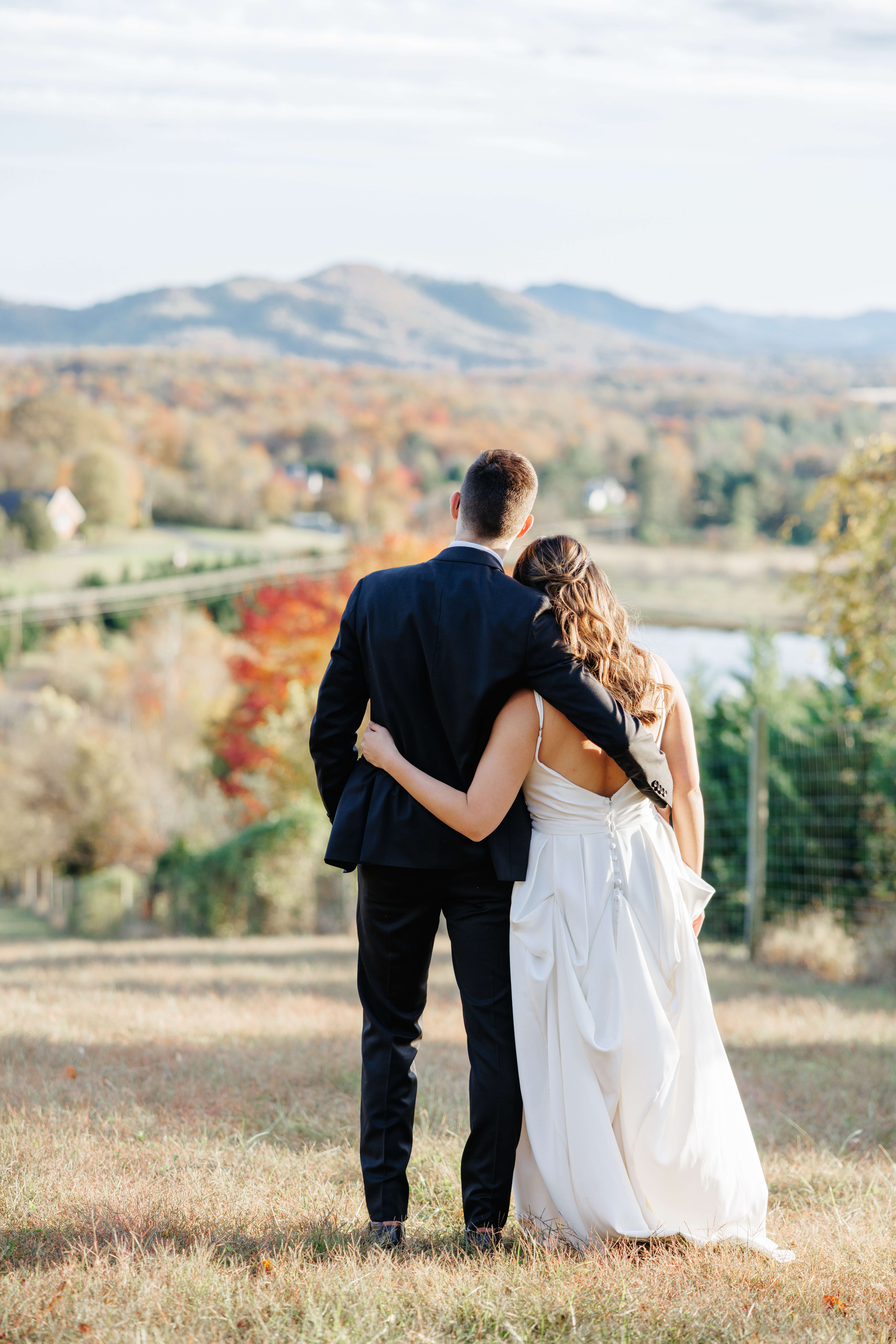 Valley Road Vineyard Fall Wedding 36 Bride and groom face away from camera looking out at the gorgeous views with their arms wrapped around one another