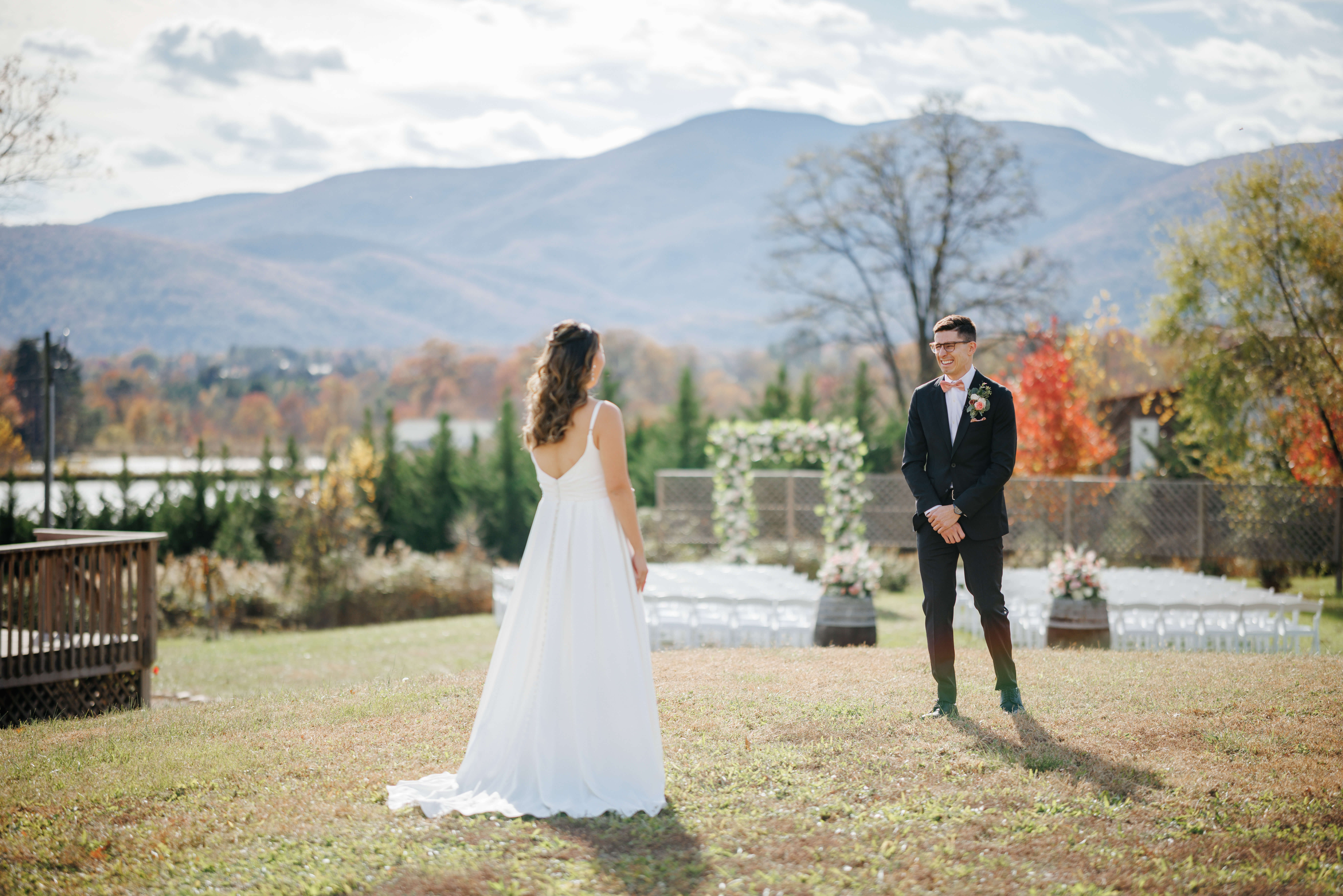 Valley Road Vineyard Fall Wedding 7 Groom turning around to see bride in her wedding dress for the first time as they stand outside in front of there ceremony set up and mountain views in background