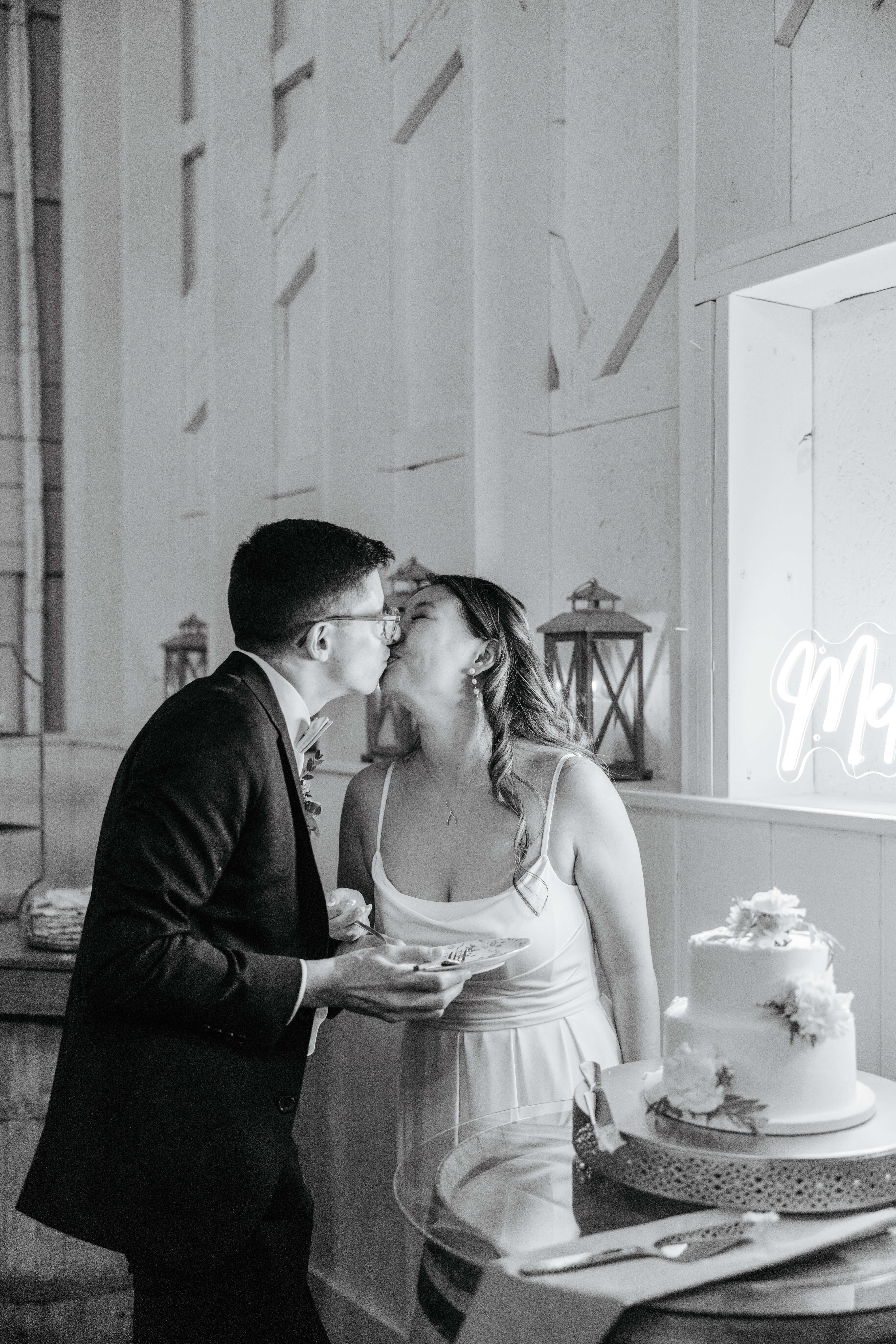 Valley Road Vineyard Fall Wedding 49 Black and white photo of bride and groom sharing a kiss after trying a bite of their wedding cake