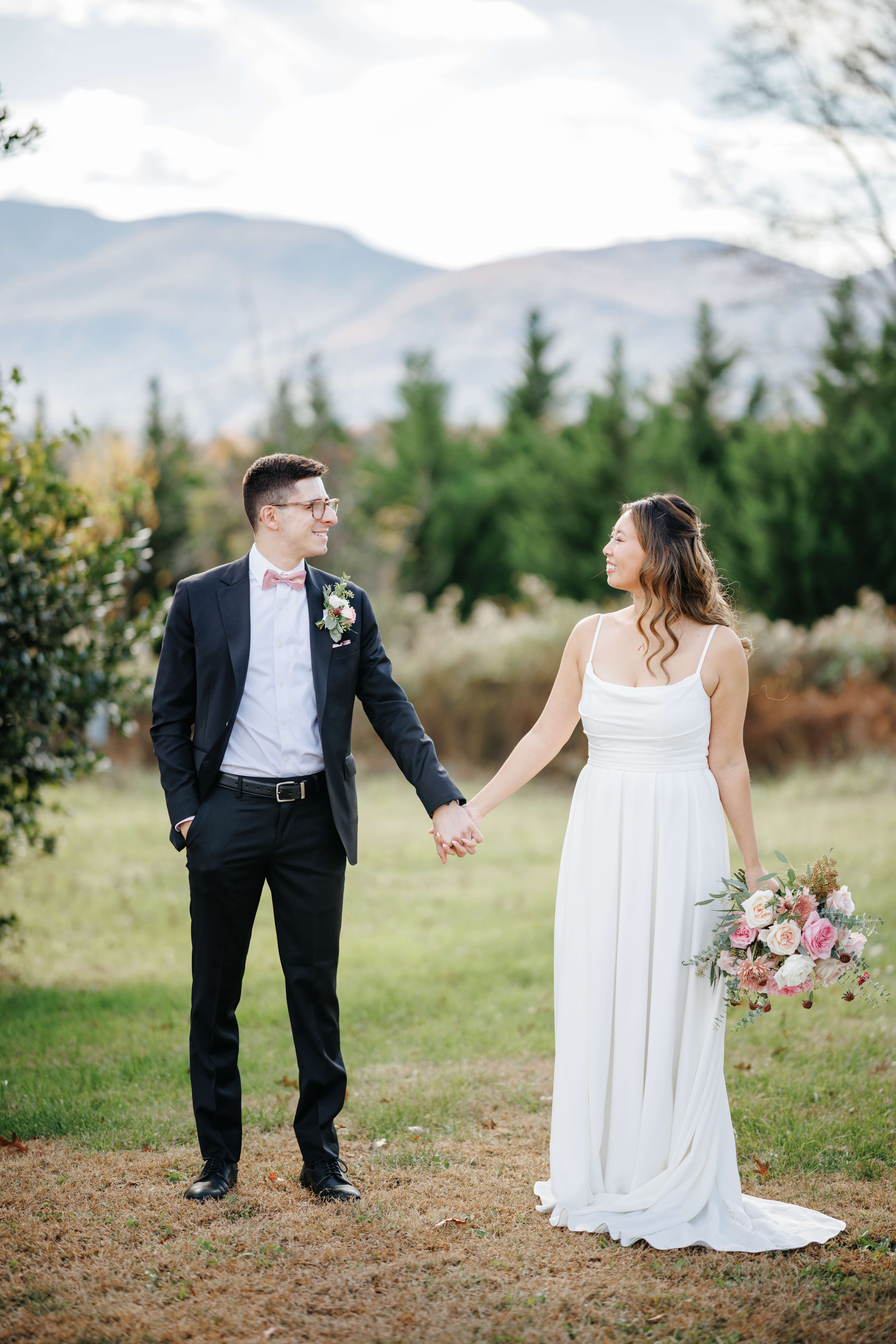 Valley Road Vineyard Fall Wedding 10 Bride and groom standing outside, mountain views in background holding hands looking at one another smiling