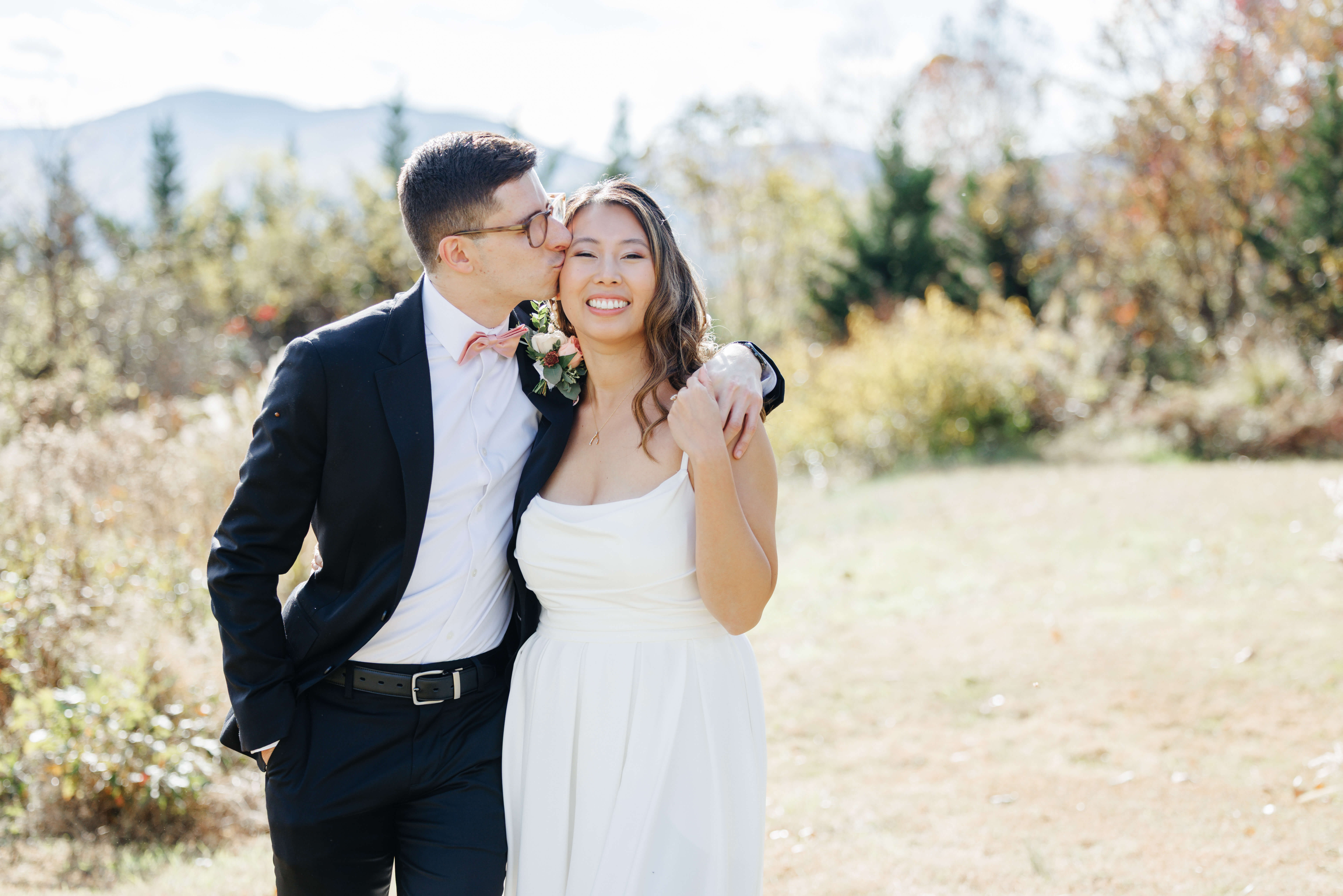 Valley Road Vineyard Fall Wedding 11 Groom wrapping his arm around bride and kissing her on the cheek as she holds his hand and smiles at camera