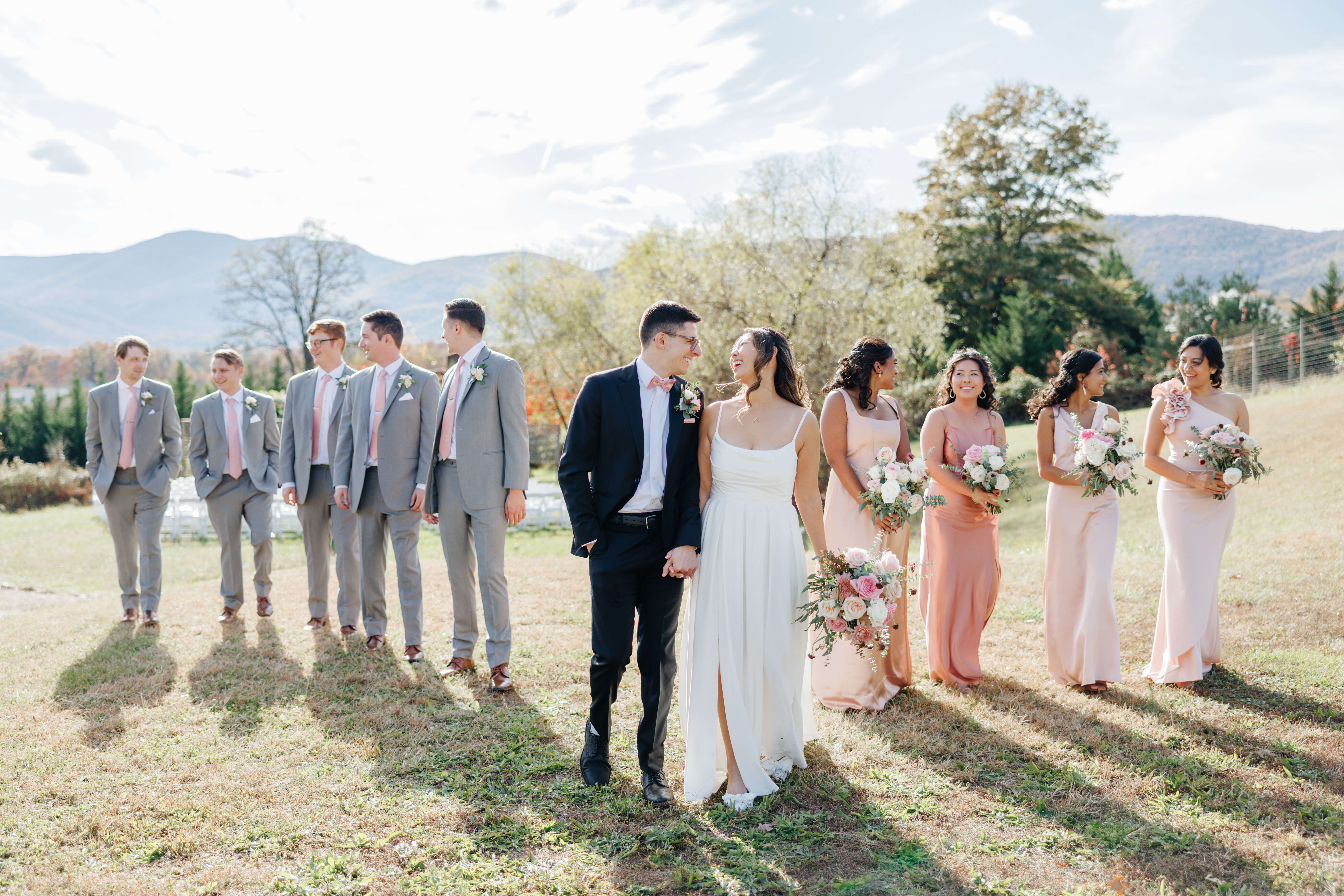 Valley Road Vineyard Fall Wedding 14 Bride and groom walk hand in hand smiling at one another, the bridesmaids and groomsmen walk staggered behind them