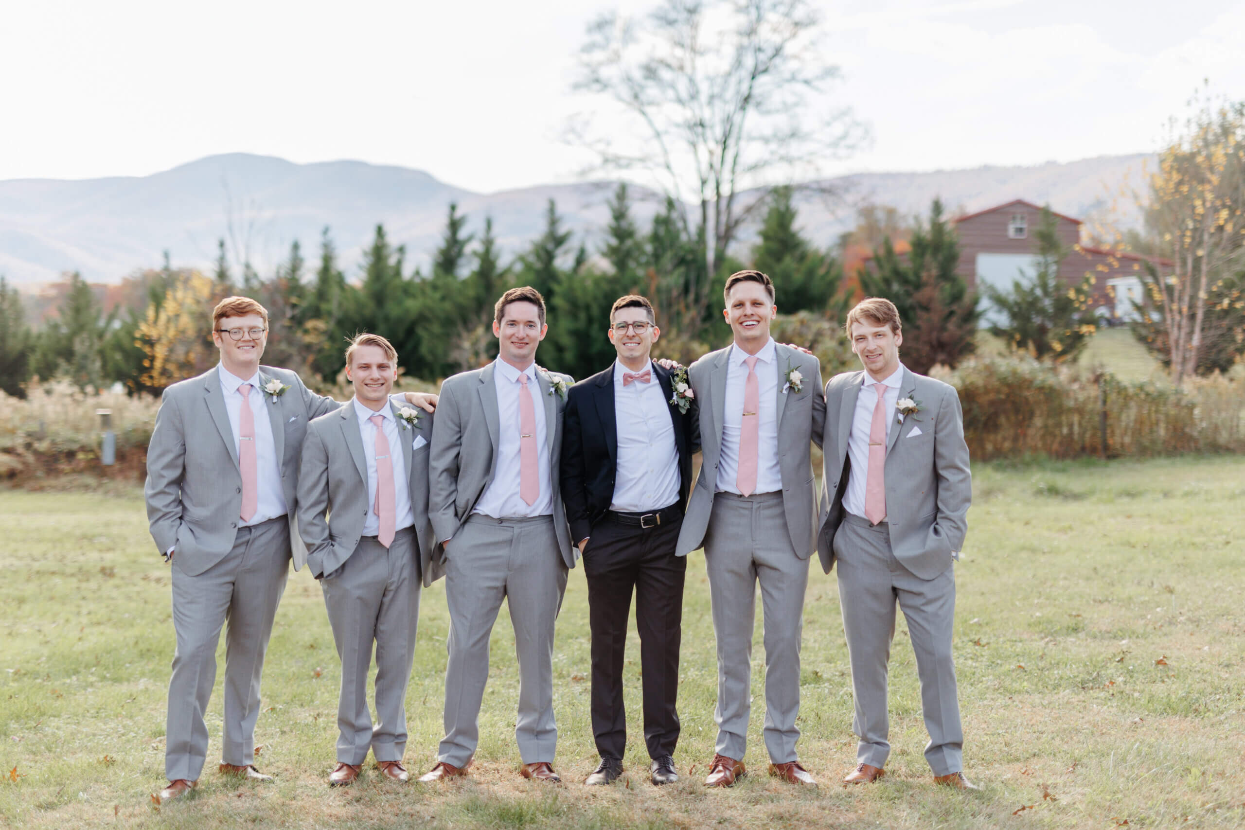 Valley Road Vineyard Fall Wedding 15 Groom stands in black suit with his five groomsmen in light grey suits with pink ties all smile at camera