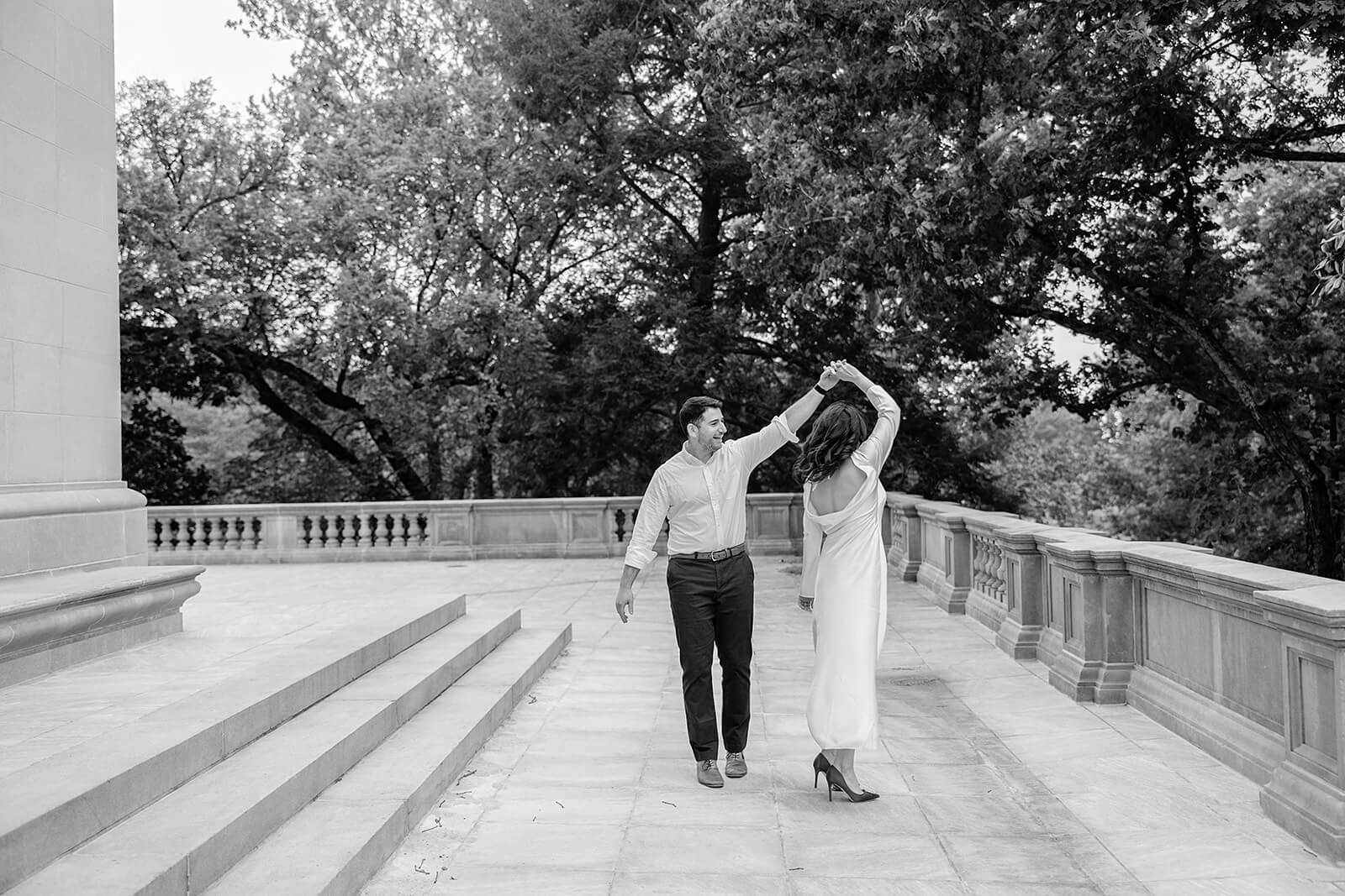 Carillon War Memorial Engagement 17 black and white photo of couple on stone patio. he is twirling her underneath his arm