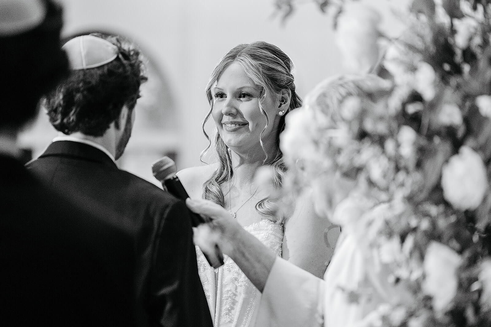 Poplar Springs Manor Spring Wedding Photography 22 black and white photo of bride smiling at groom as he says his vows