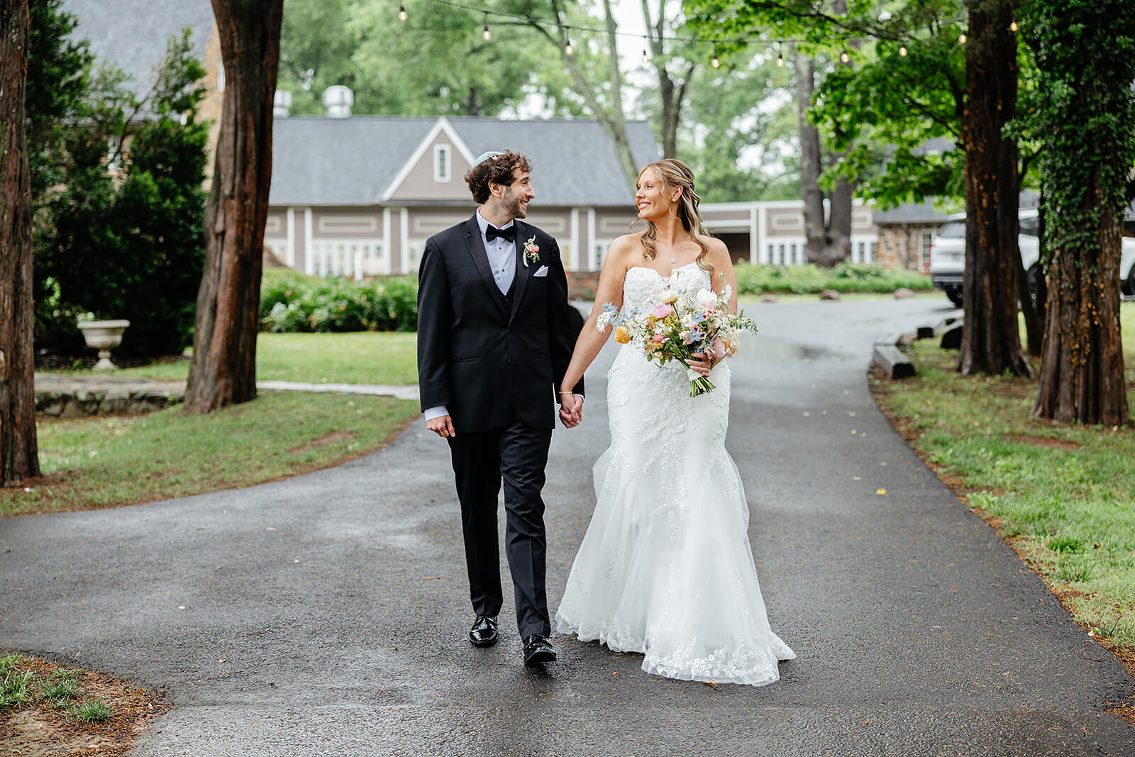 Poplar Springs Manor Spring Wedding Photography 25 bride and groom holding hands as they walk down a wooded path away from the venue