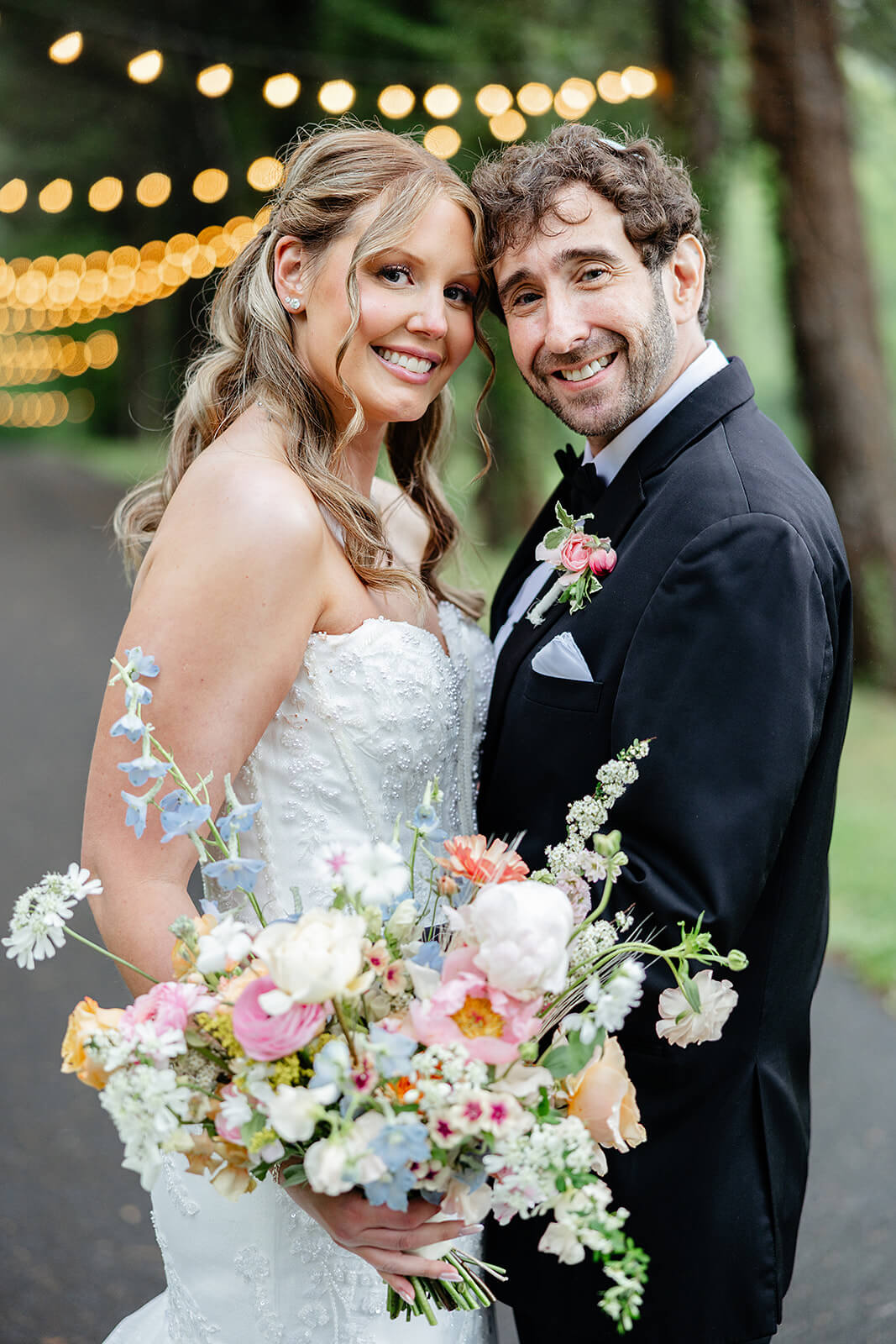 Poplar Springs Manor Spring Wedding Photography 28 hey are standing by a wooded path with string lights in the background
