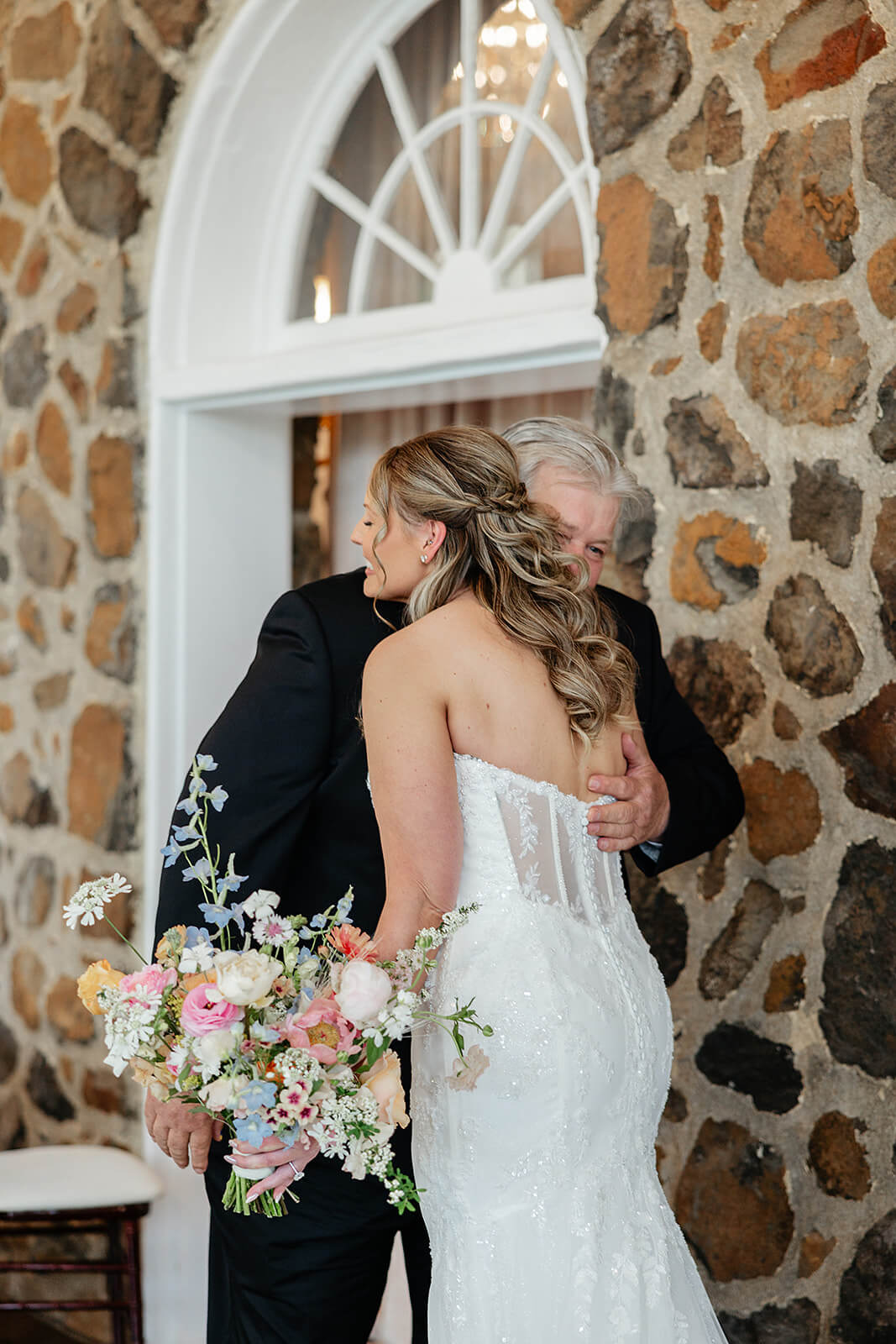 Poplar Springs Manor Spring Wedding Photography 12 bride hugging her dad by a large stone wall