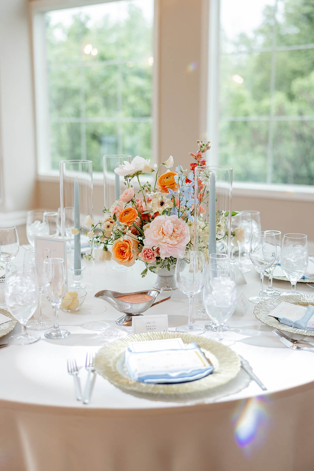 Poplar Springs Manor Spring Wedding Photography 14 reception table with blue accented place settings, blue candlesticks, and orange, pink, and light blue florals