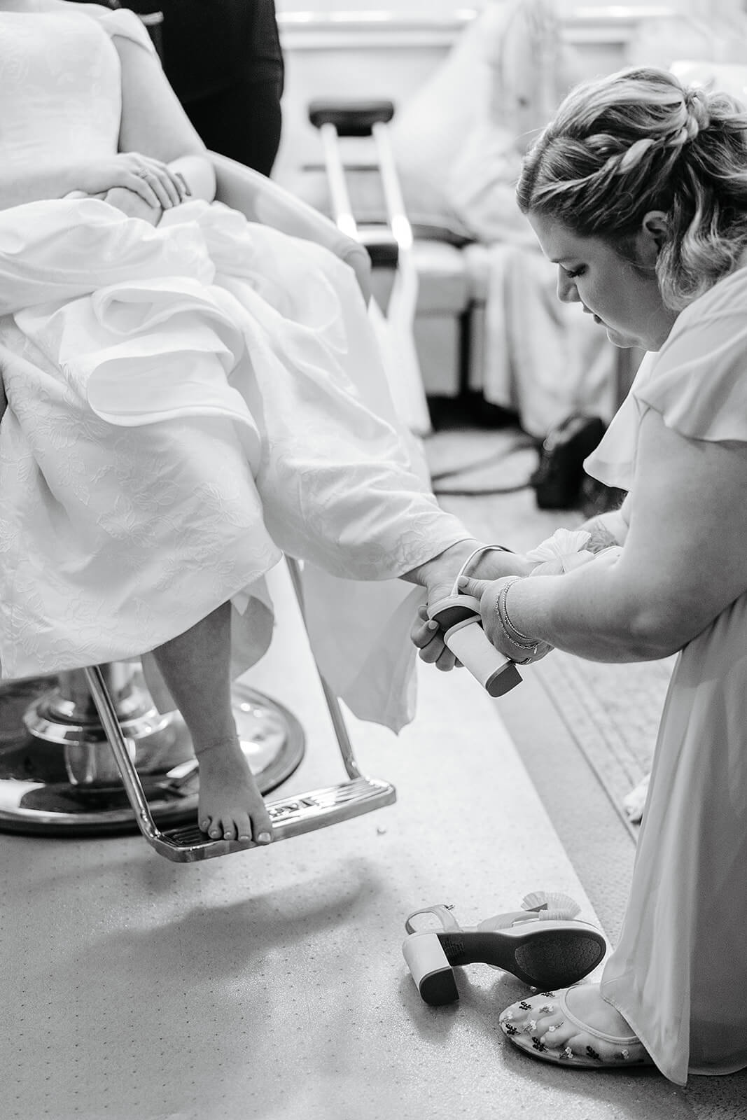The Mill at Fine Creek Spring Wedding Photography in Powhatan 11 black and white photo of bridesmaid helping the bride with her shoes
