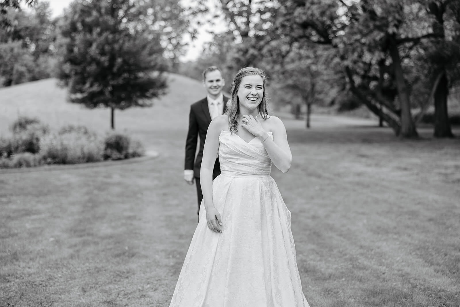 Allegheny RiverTrail Park Spring Wedding Photography 27 black and white photo of bride smiling while groom walks up to her from behind