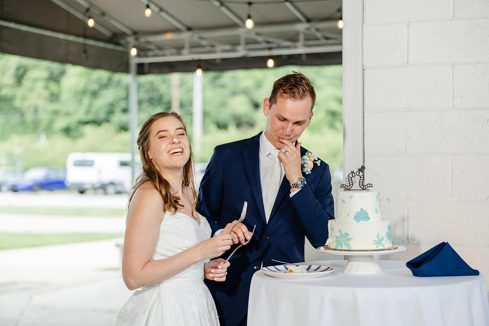 Allegheny RiverTrail Park Spring Wedding Photography 37 bride and groom cutting cake, there is icing on the bride's nose and the groom is licking his fingers