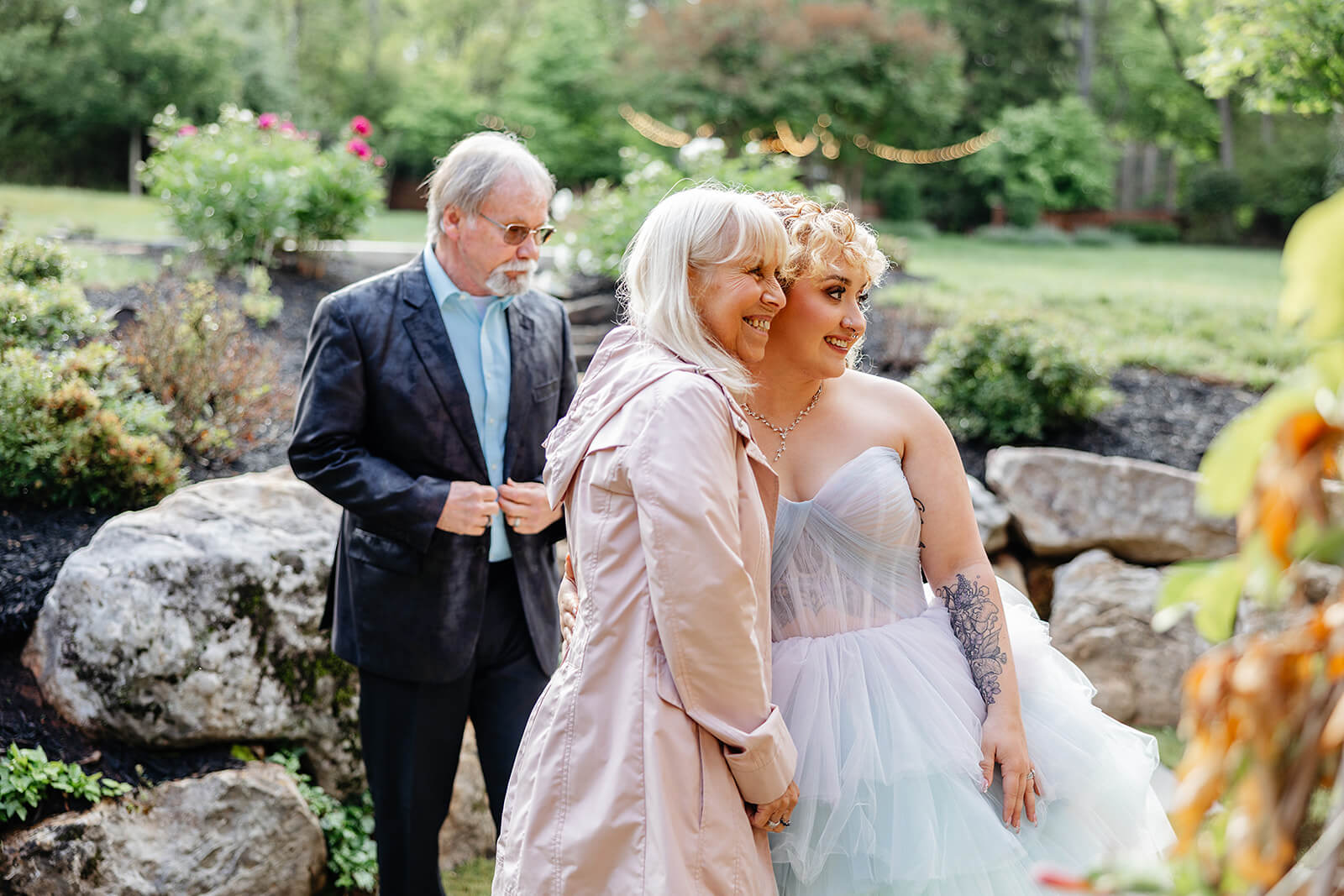 Vaughan Greenhouse Spring Wedding Photography 25 bride hugging guests in front of a yard with a rock pile