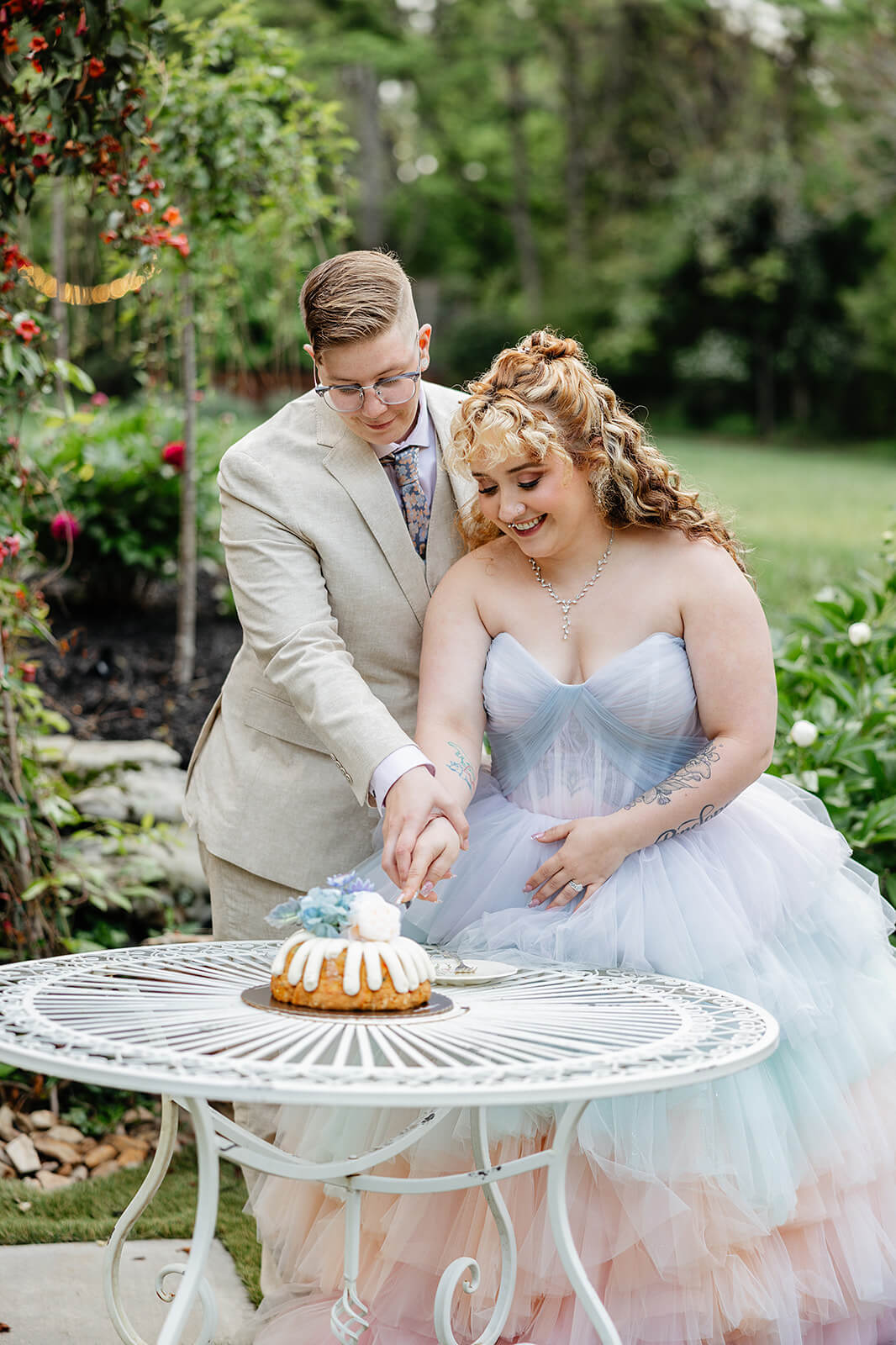 Vaughan Greenhouse Spring Wedding Photography 30 bride and groom cutting their cake sitting on a white garden table