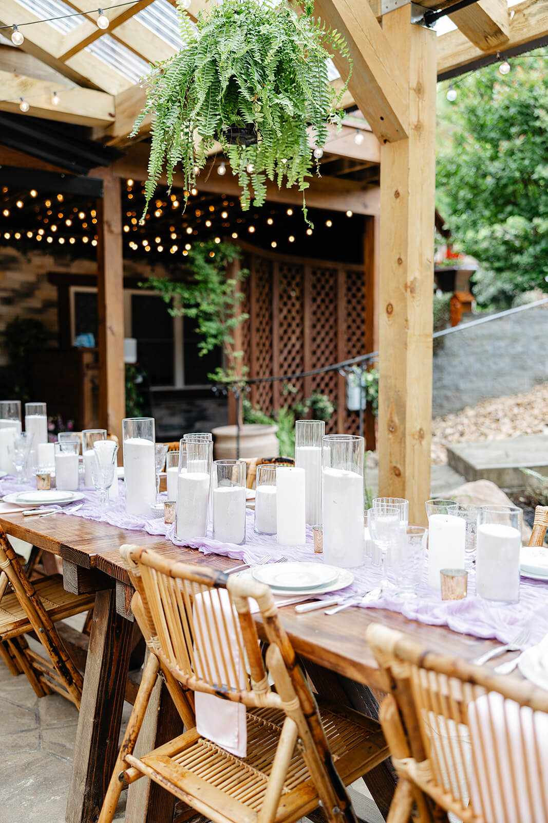 Vaughan Greenhouse Spring Wedding Photography 5 reception table with wooden chairs, lots of class candles, and greenery hanging from rafters