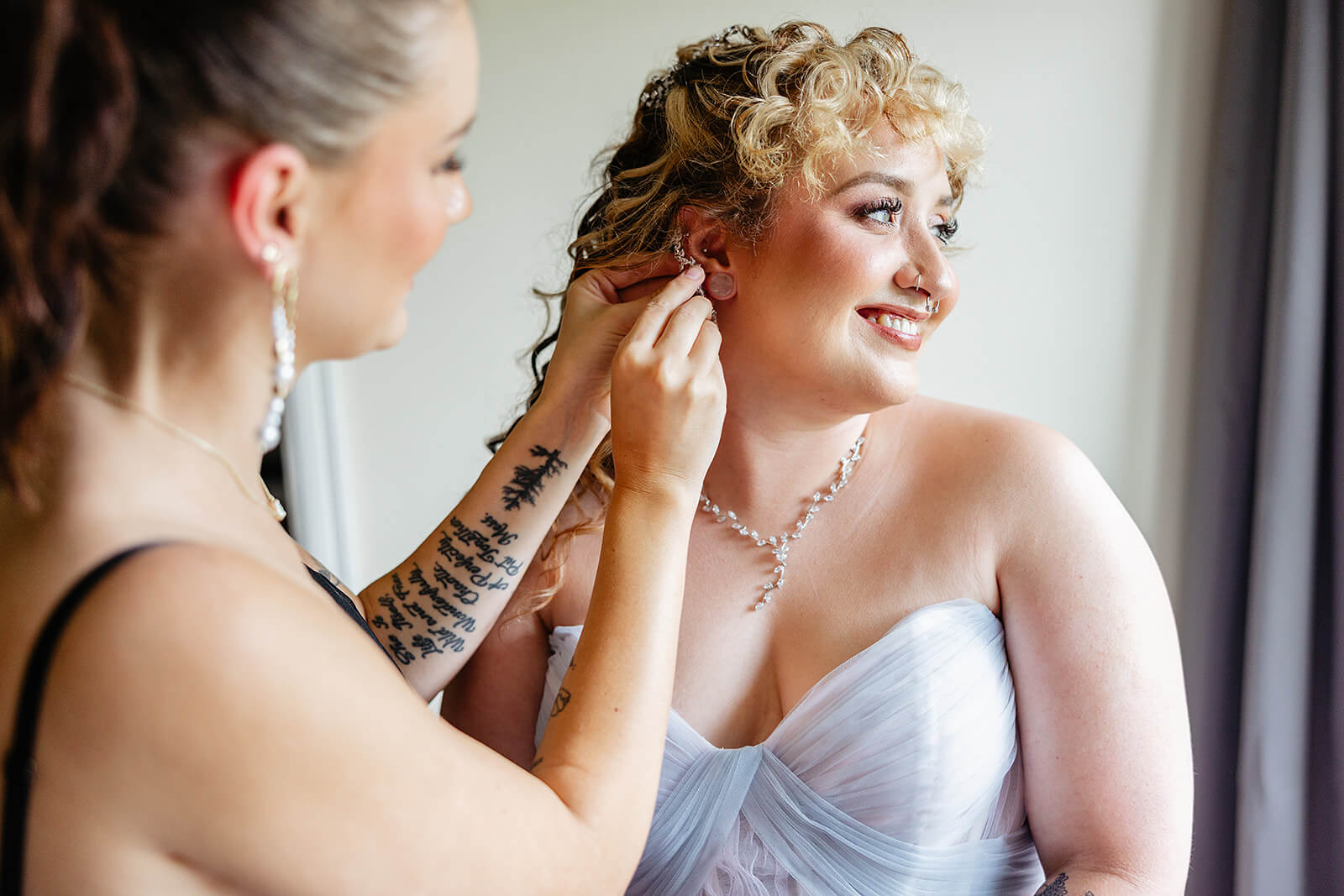 Vaughan Greenhouse Spring Wedding Photography 3 friend helping smiling bride put her earrings on
