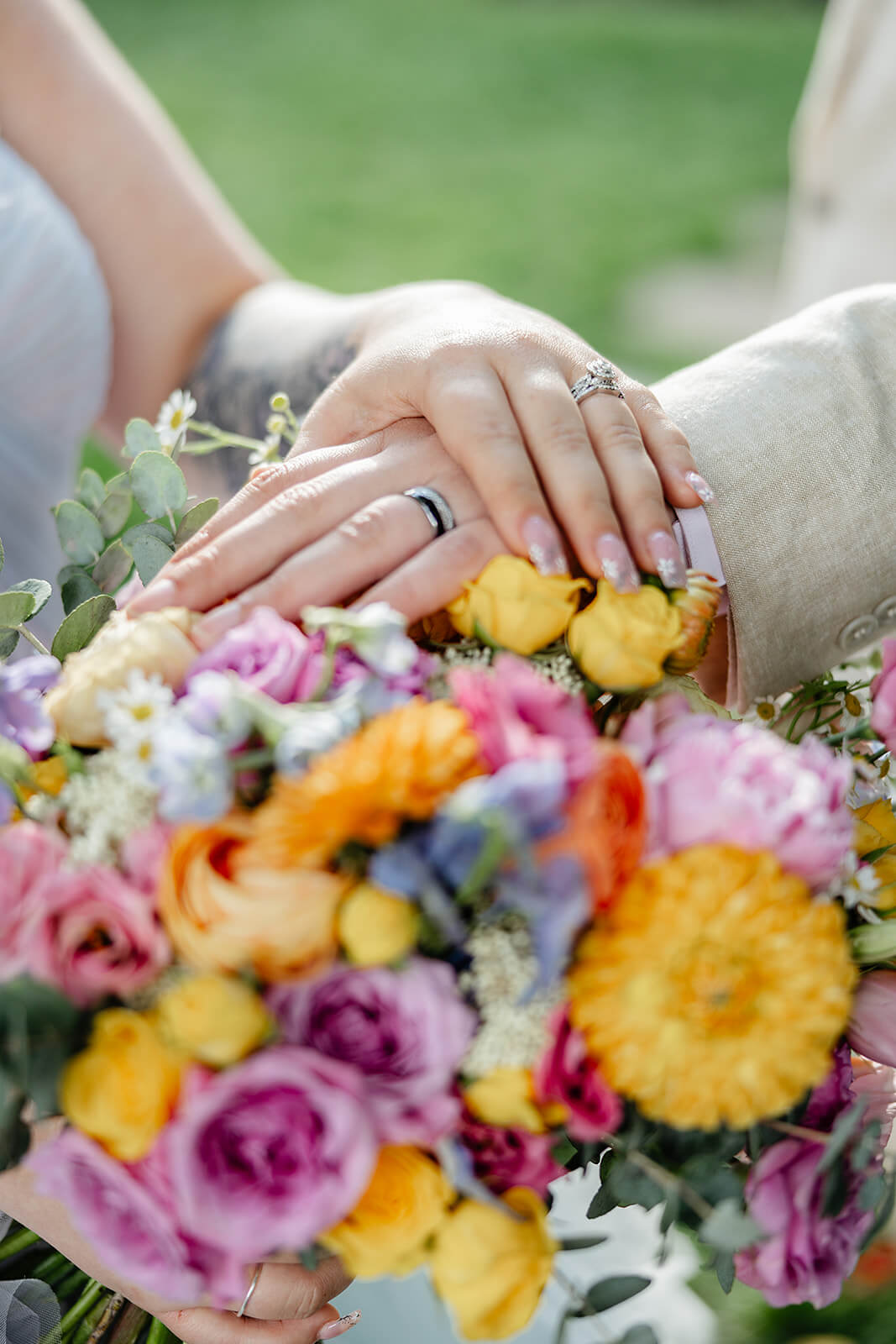 Vaughan Greenhouse Spring Wedding Photography 15 detail photo of the couple's rings and the bride's bouquet of rainbow flowers