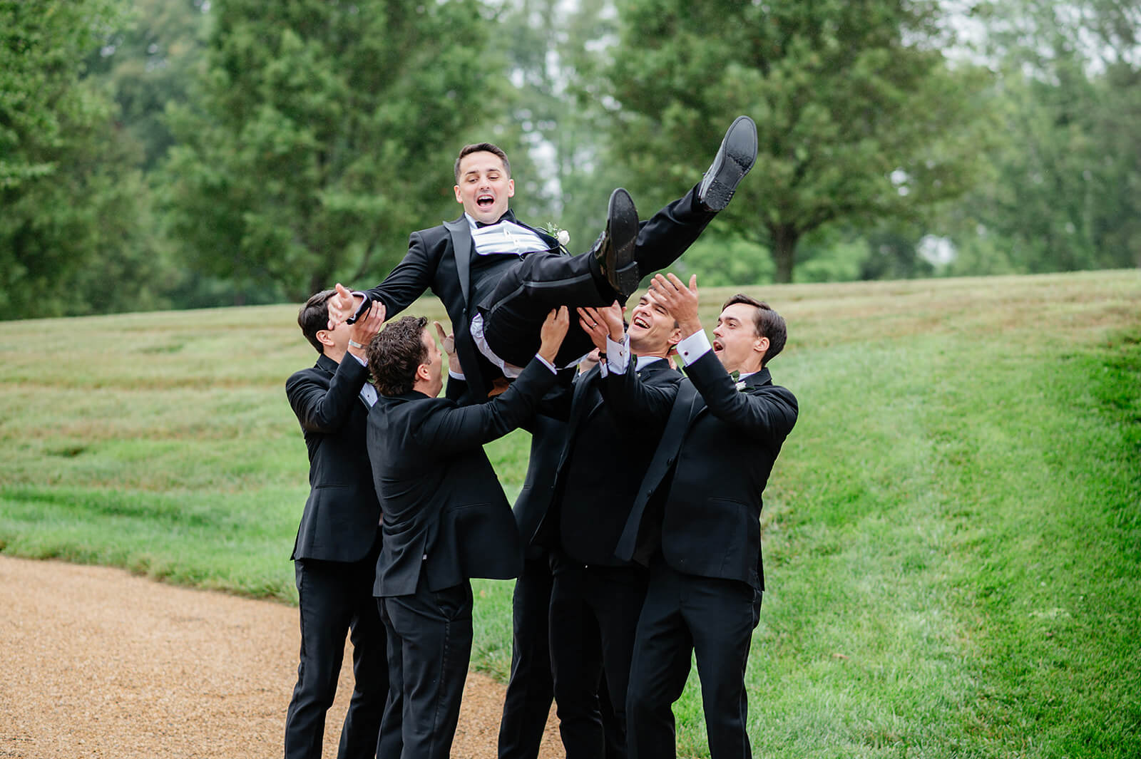 Matt + Adriana's May Wedding Photography 19 groomsmen holding the groom and tossing him up in the air