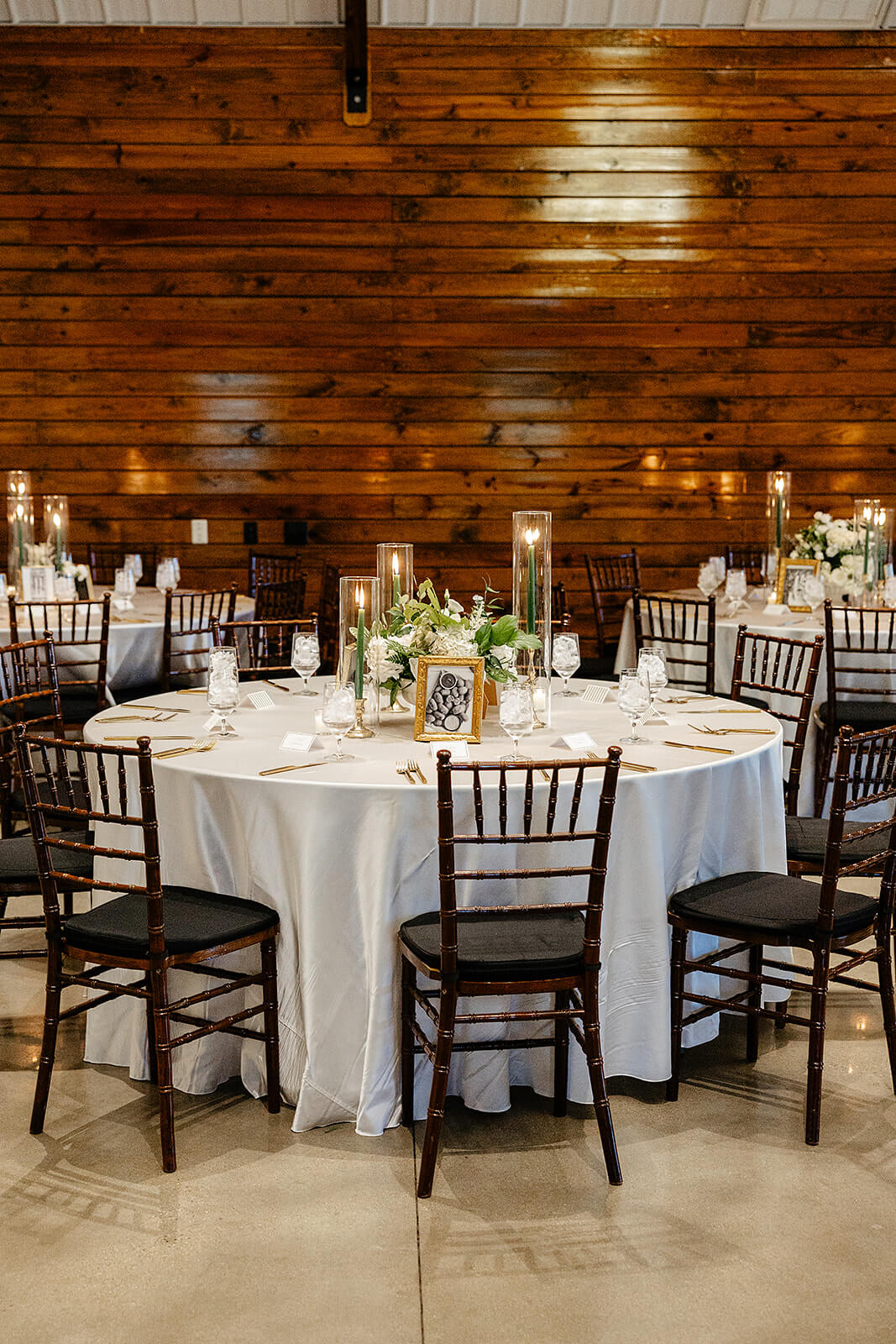 Matt + Adriana's May Wedding Photography 27 reception table with dark chairs around it and gold place settings and tall candles on the table