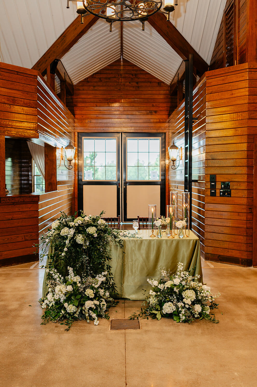 Matt + Adriana's May Wedding Photography 28 sweetheart table with green table clothe and huge green and while floral arrangements seeping over the table on the floor