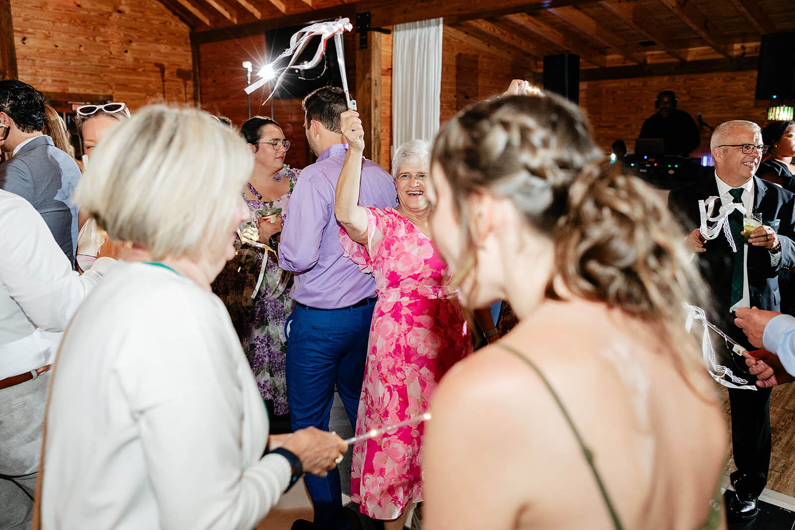 Matt + Adriana's May Wedding Photography 36 older woman in pink dress waving ribbons and dancing with other guests