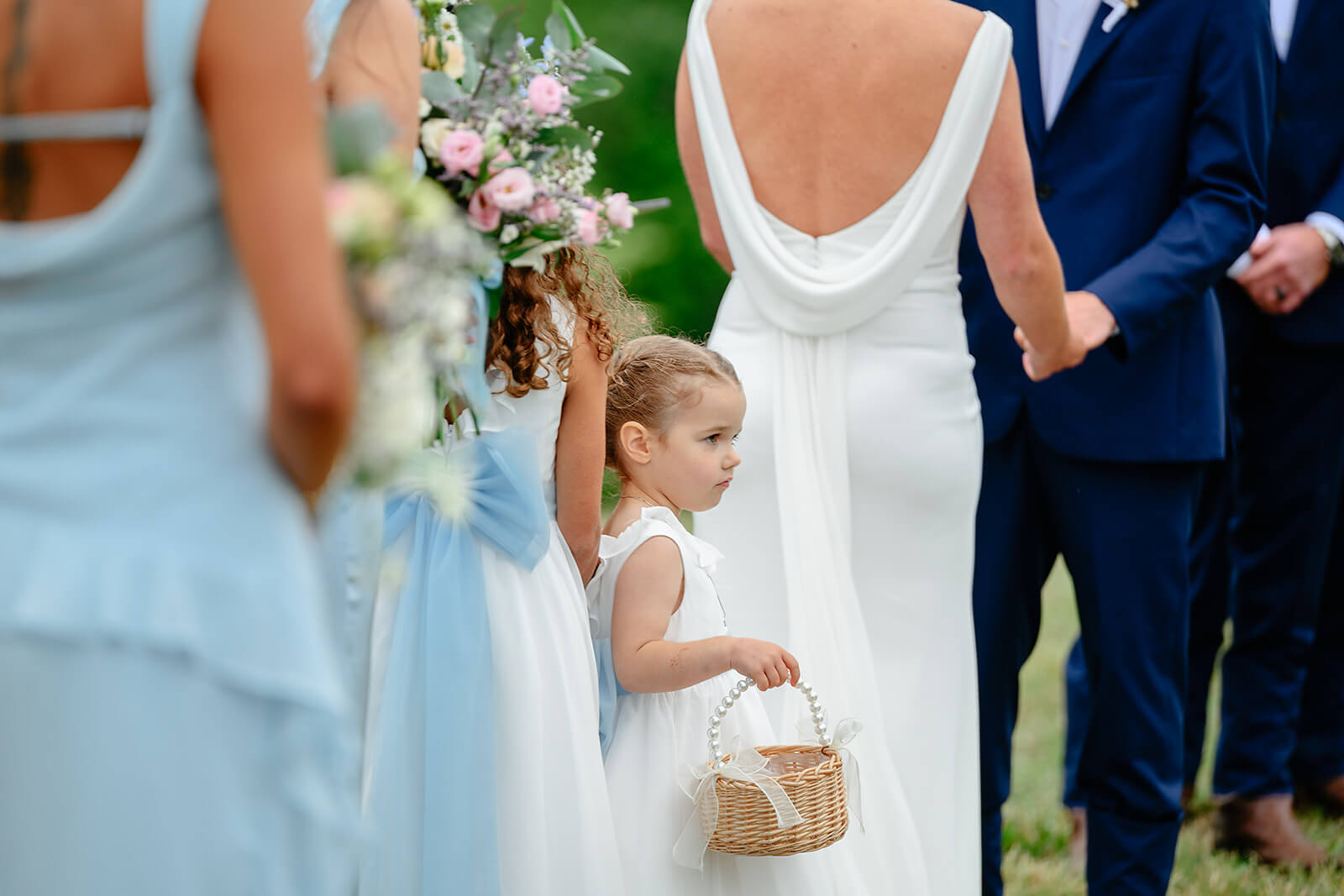 Family Farm Spring Wedding Photography 21 flower girl holding whicker basket with pearl handle standing behind bride