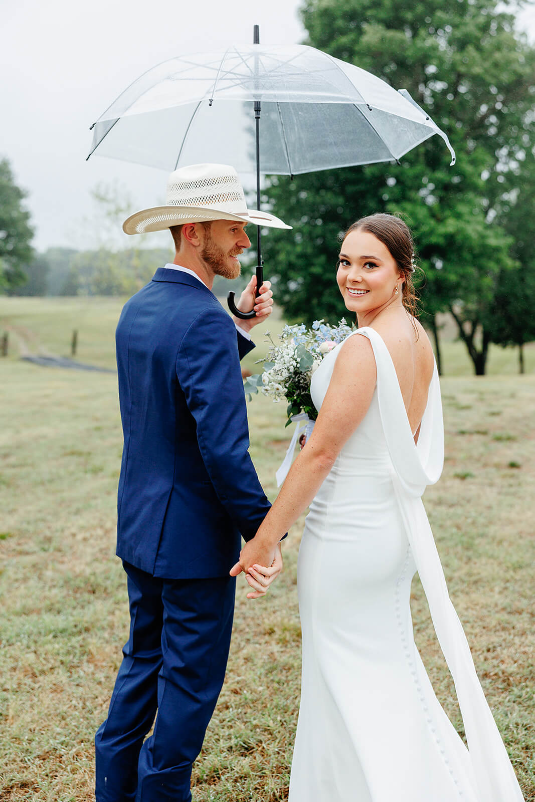 Family Farm Spring Wedding Photography 27 bride and groom covered by an umbrella and smiling at each other and the camera
