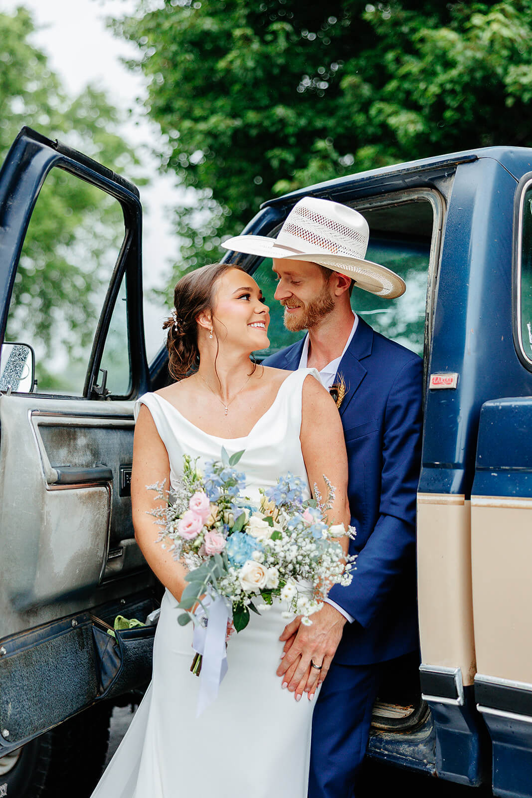 Family Farm Spring Wedding Photography 30 bride and groom standing together and looking at each other in the open door of an old truck