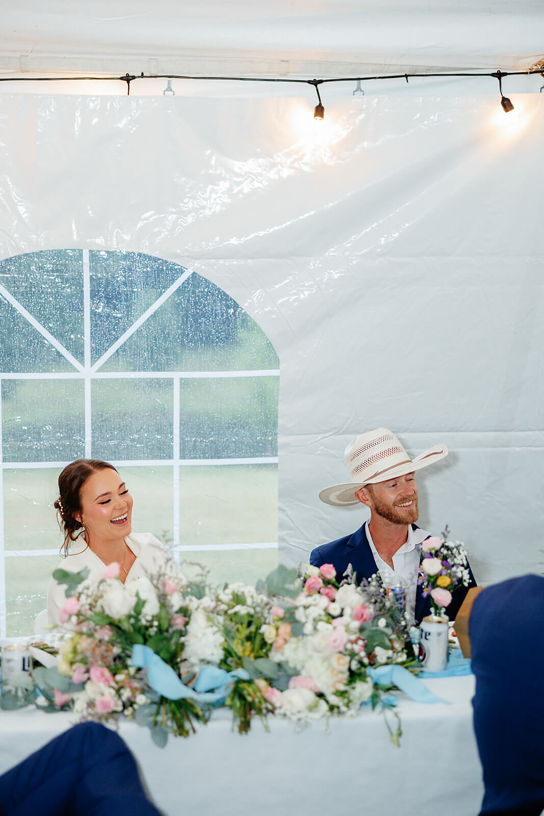 vFamily Farm Spring Wedding Photography 39 bride and groom sitting at their table, laughing at a speech