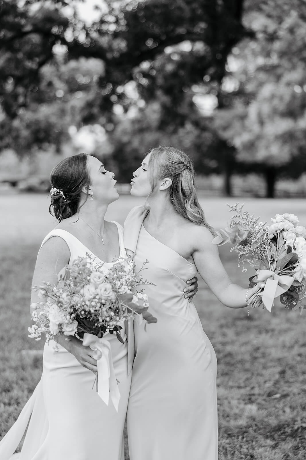 Family Farm Spring Wedding Photography 9 black and white photo of bride and bridesmaid holding bouquets and pretending to kiss each other