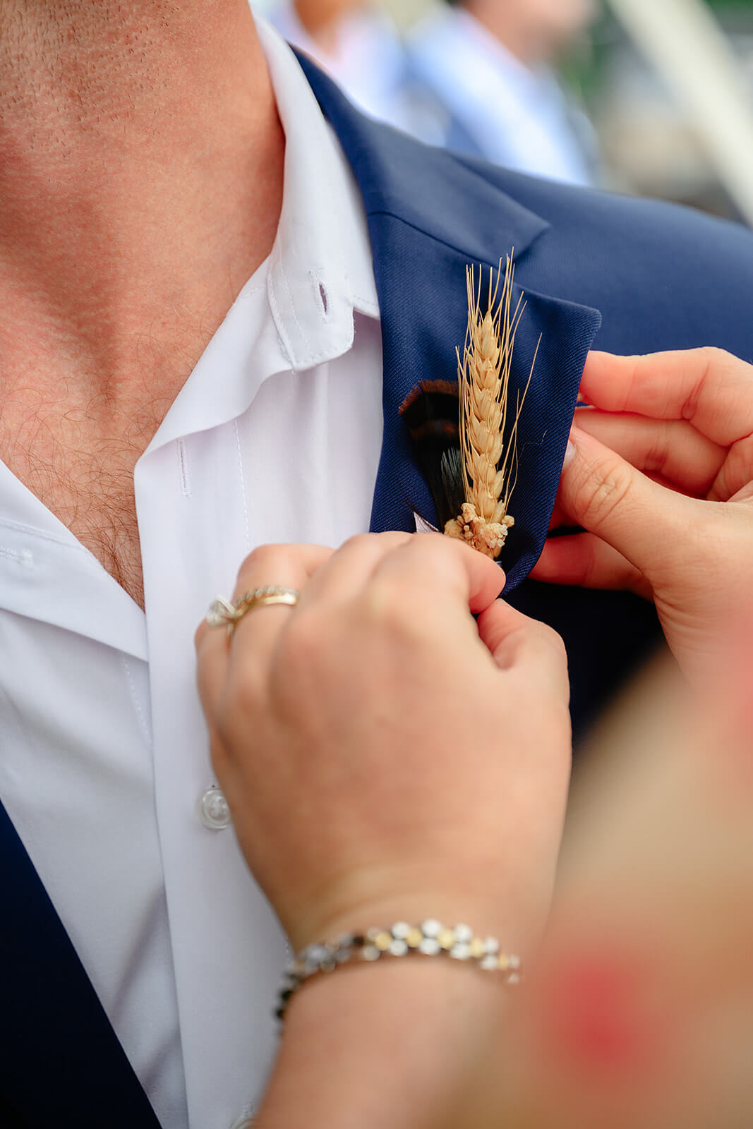 Family Farm Spring Wedding Photography 3 groom getting wheat stalk pinned into his jacket button hole