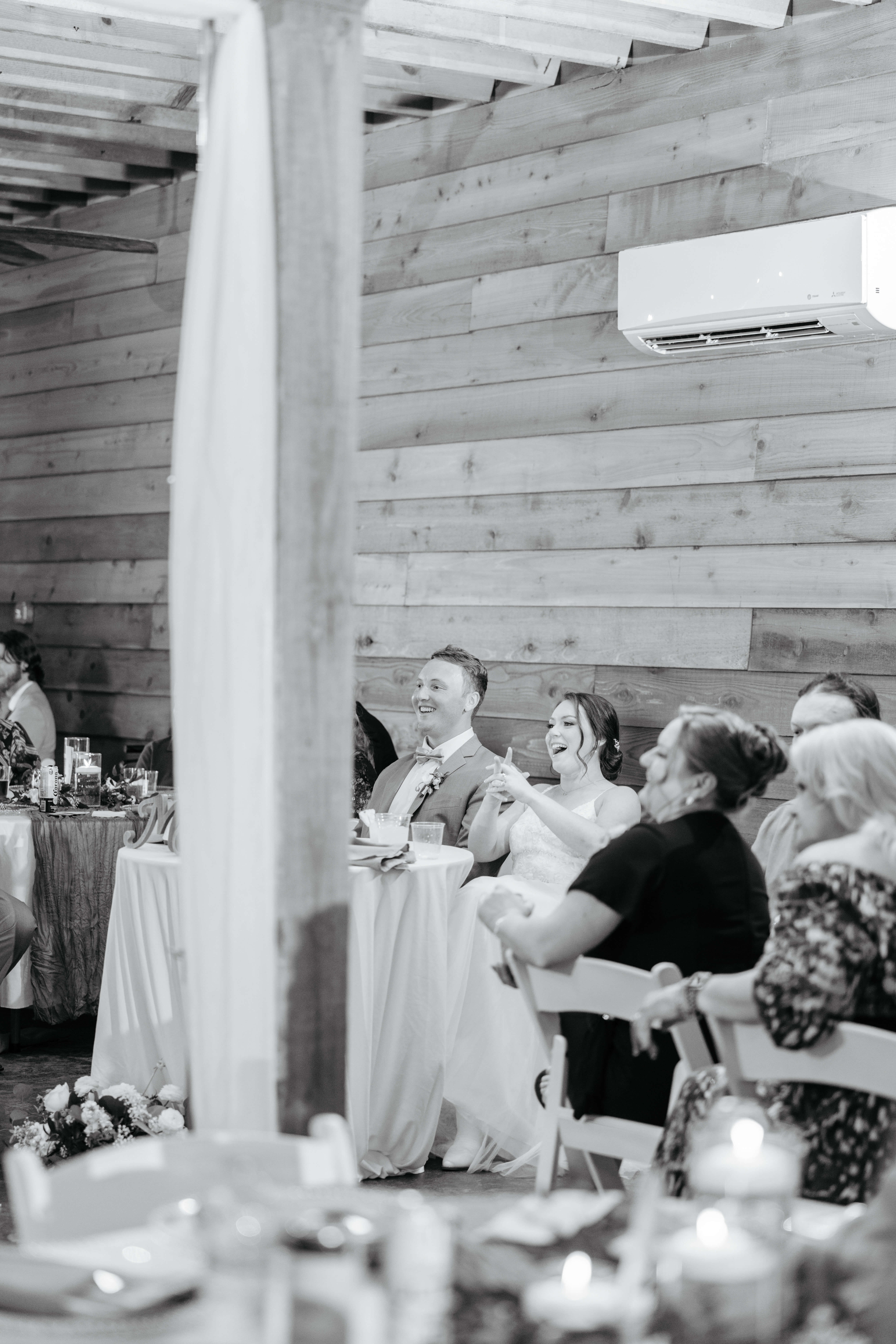 Malden Hill Spring Wedding Photography 25 black and white phot of bride and groom laughing as they listen to a speech