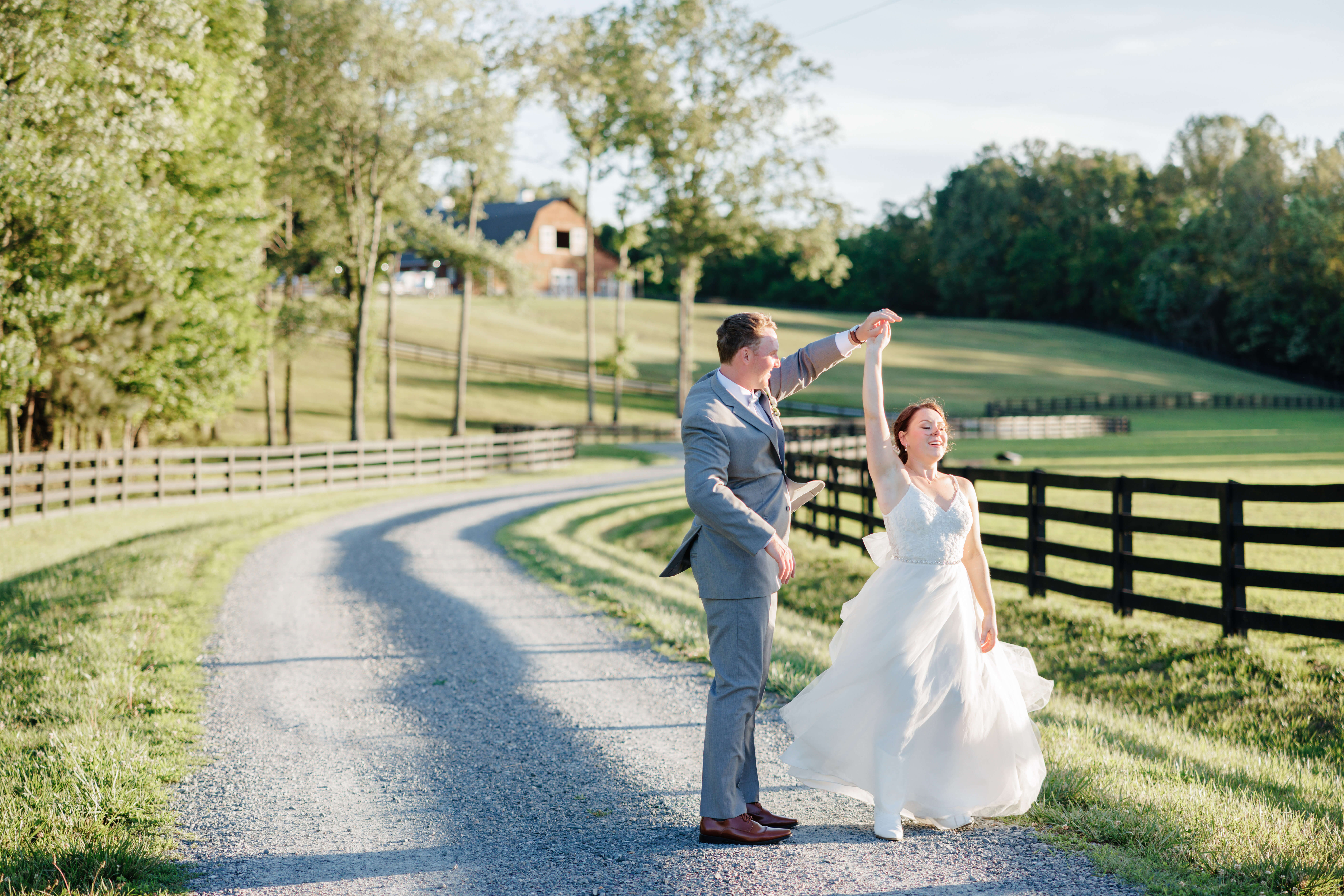 Malden Hill Spring Wedding Photography 34 groom twirling bride on gravel driveway with barn in the background