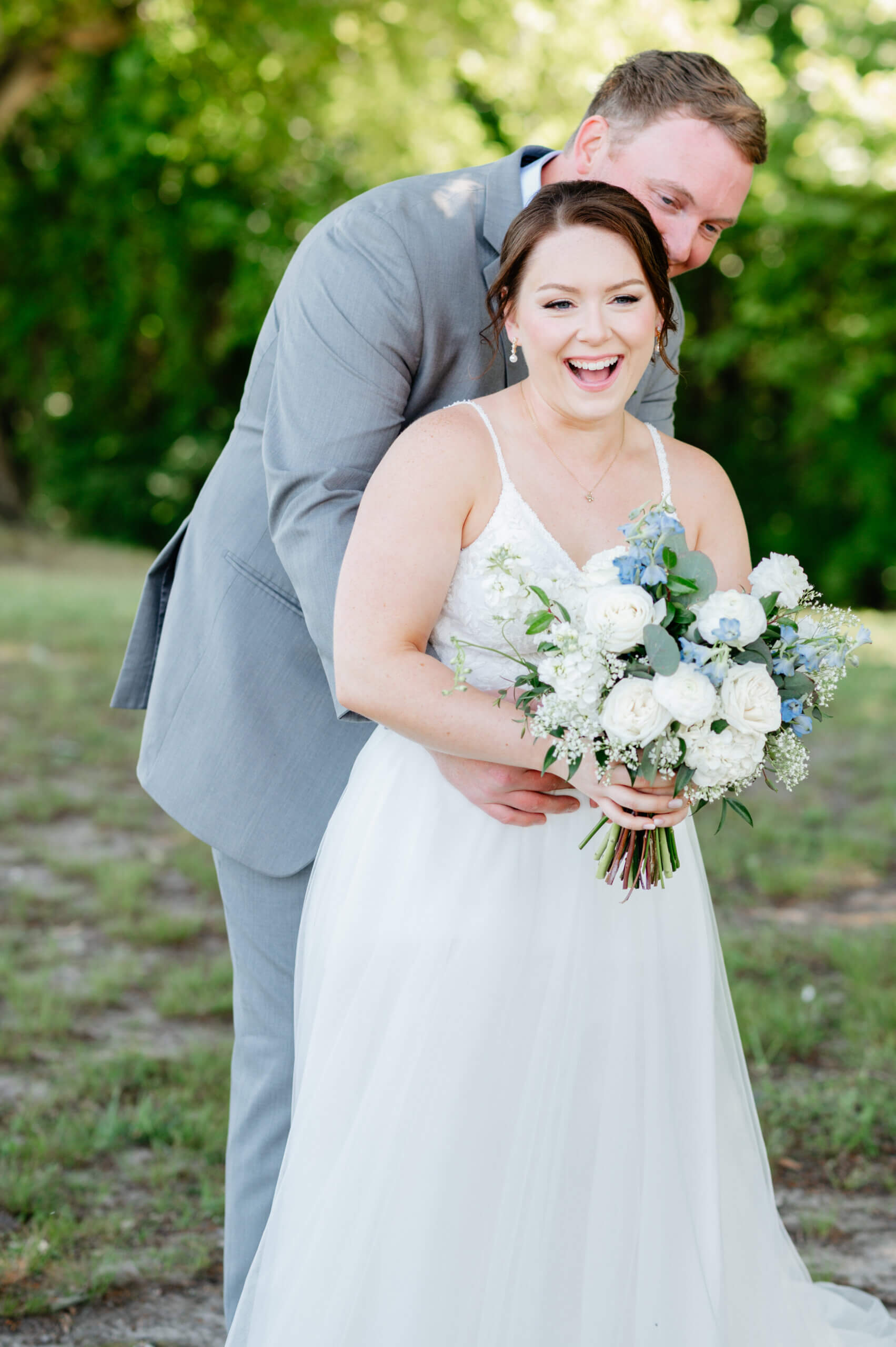 Malden Hill Spring Wedding Photography 14 groom hugging bride from behind, she is smiling and holding her bouquet