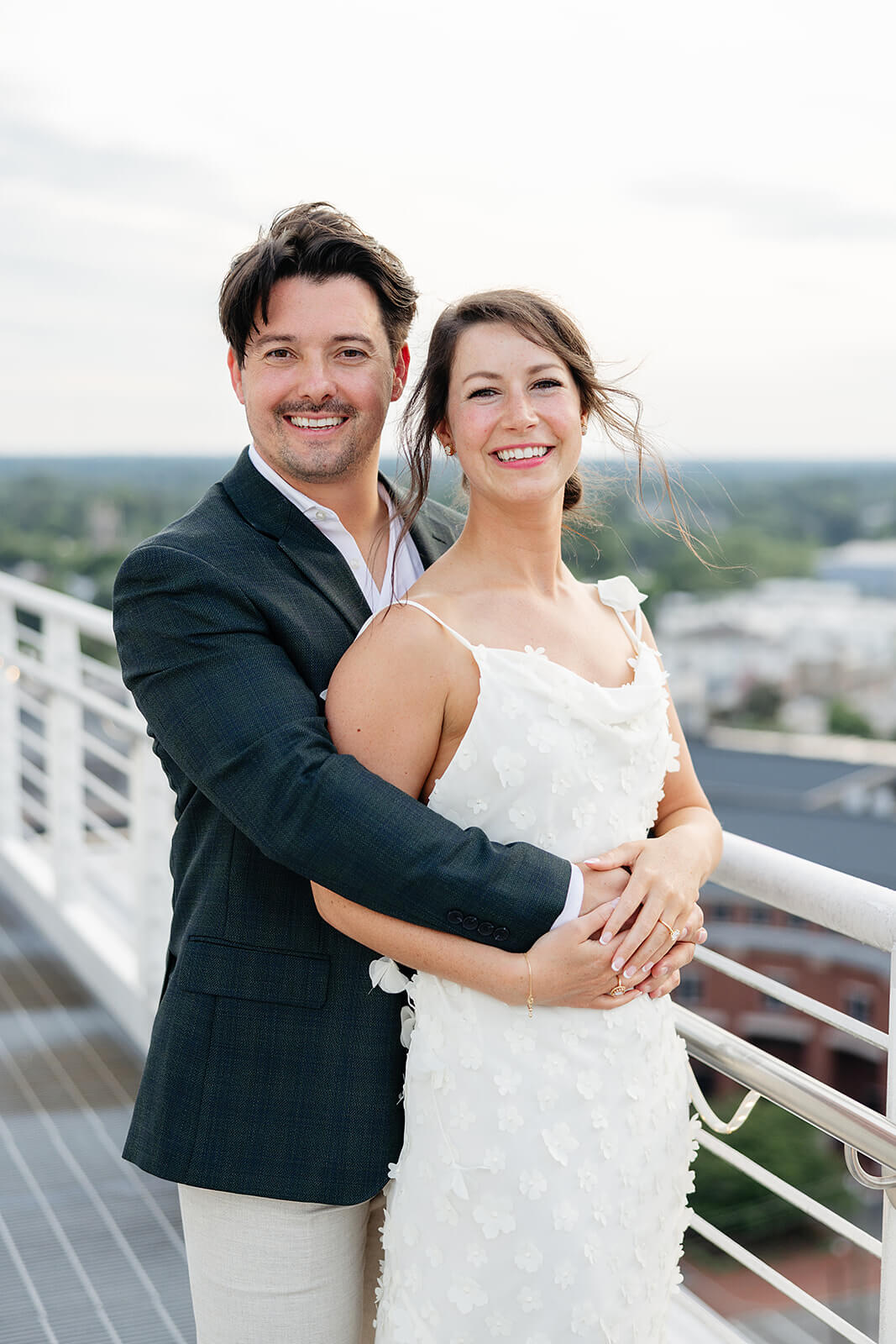 Estate at River Run Summer Wedding Photography 3 portrait of bride and groom on deck of downtown building, they are facing the camera and he is hugging her from behind
