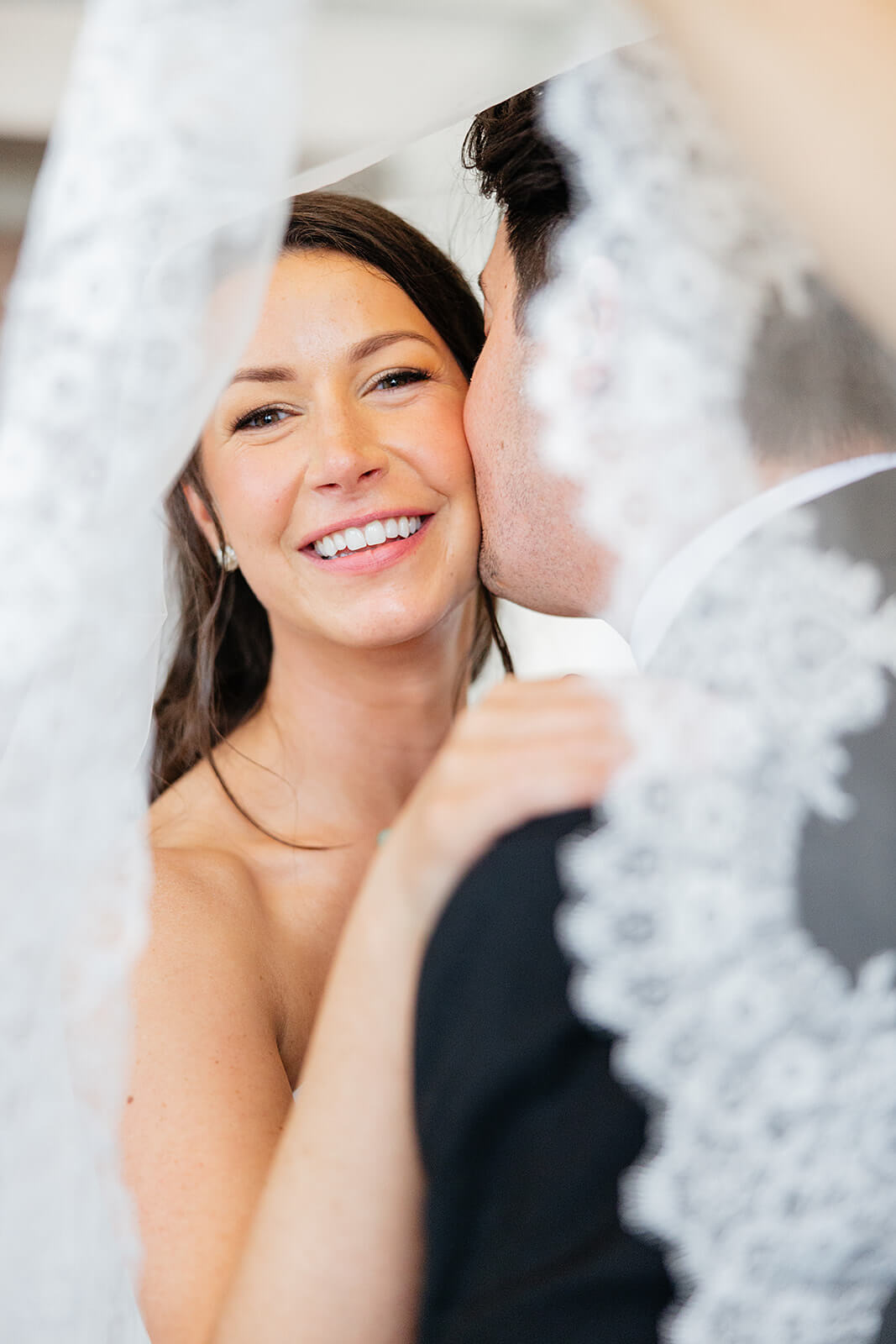 Estate at River Run Summer Wedding Photography 28 bride being kissed on the cheek by her husband underneath the veil